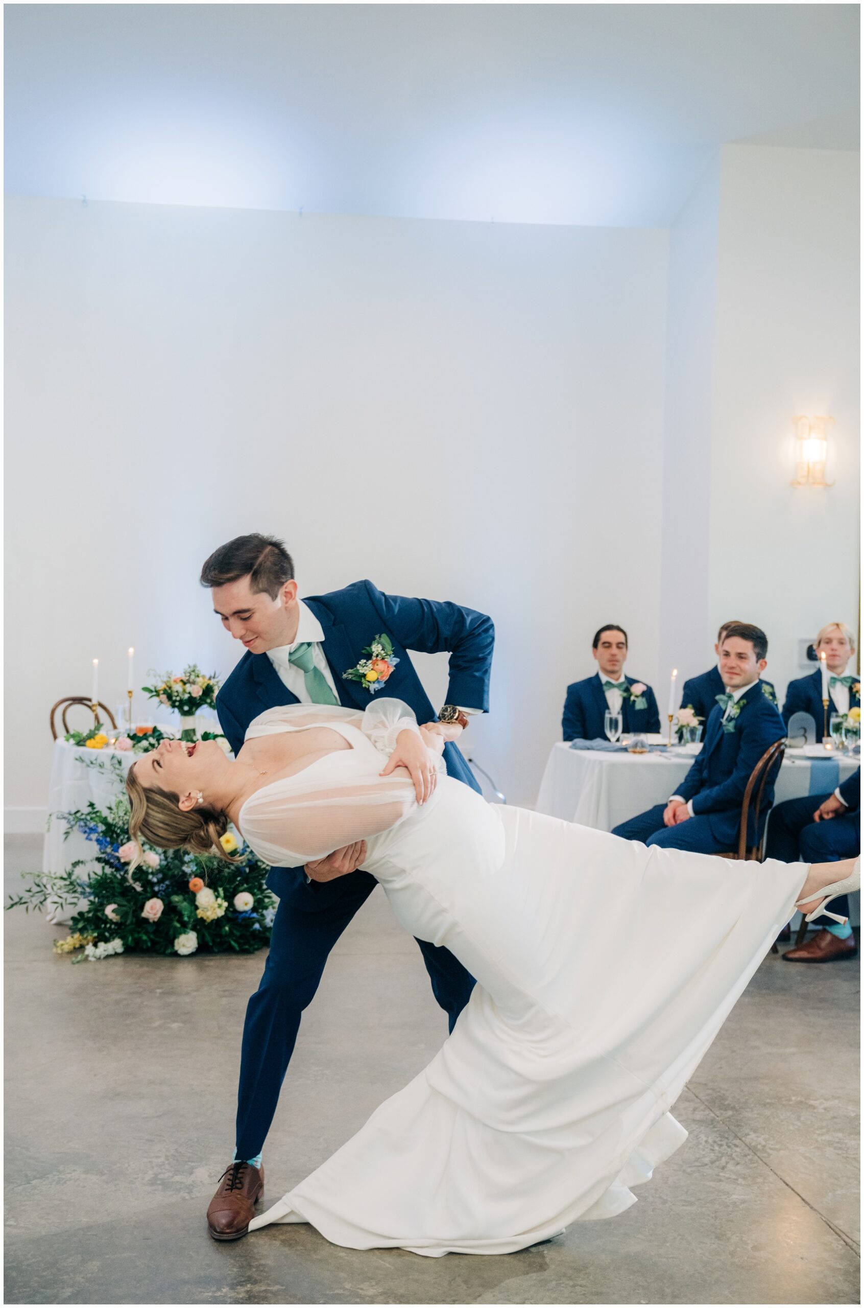 A groom dips his happy bride while dancing at their reception