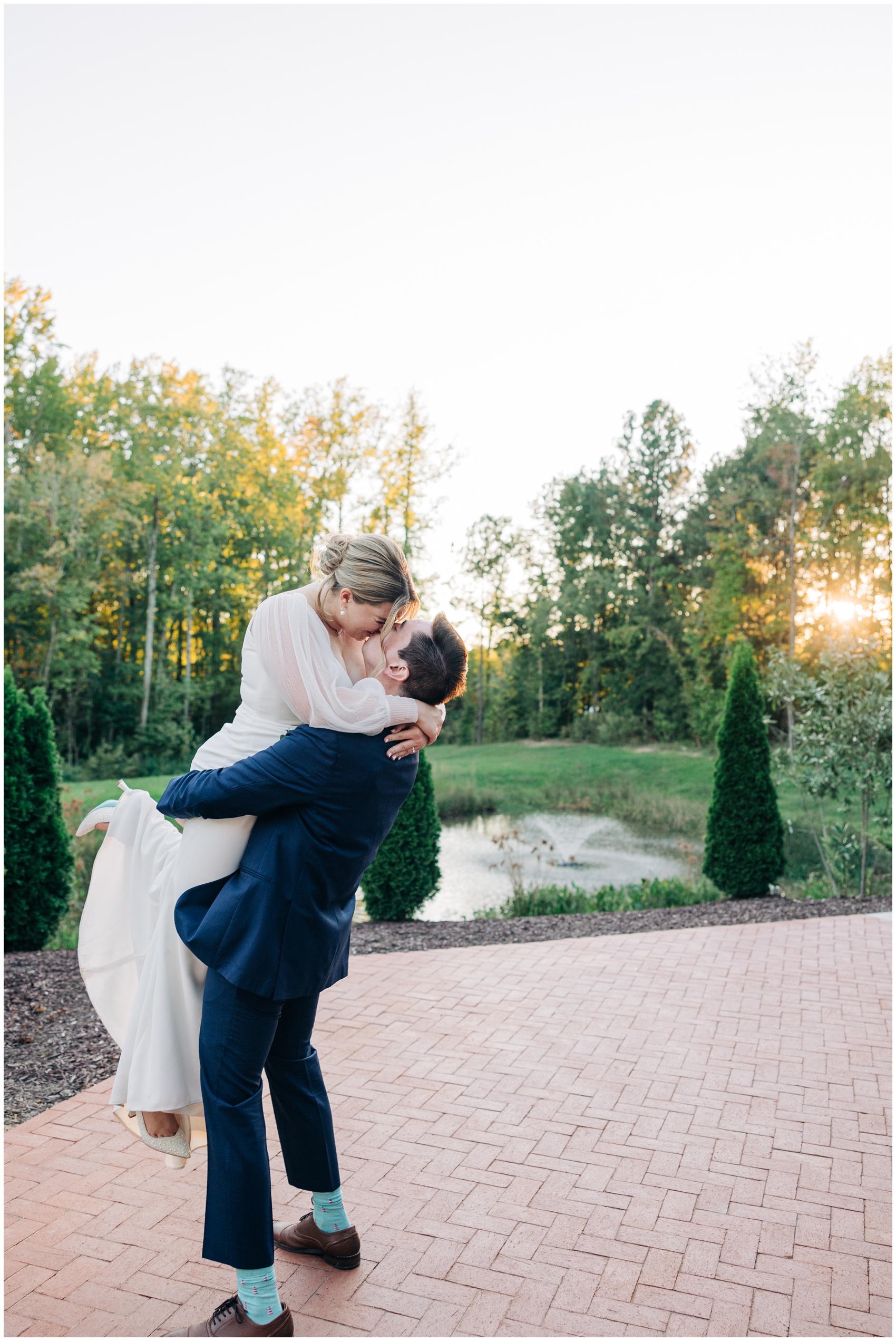 A groom lifts and kisses his bride on the brick patio at the upchurch wedding venue