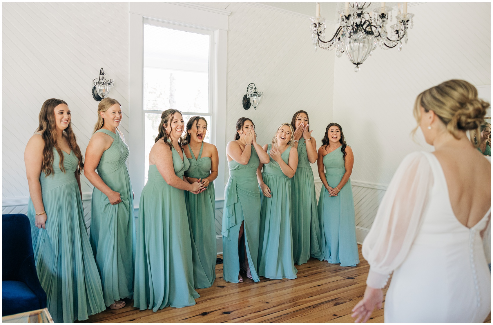 A group of bridesmaids happily cheer while seeing the bride for the first time