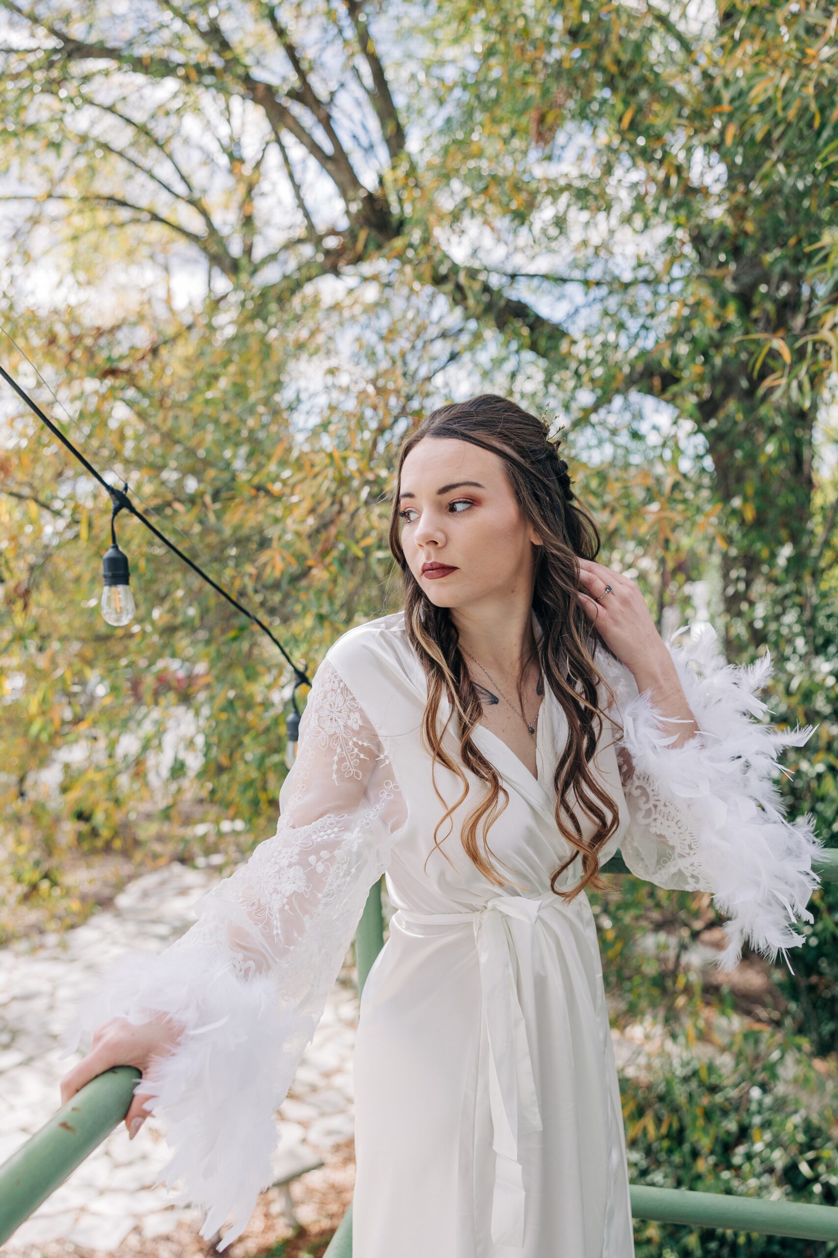 A bride gazes over her shoulder from the balcony of The Finch House in a white robe