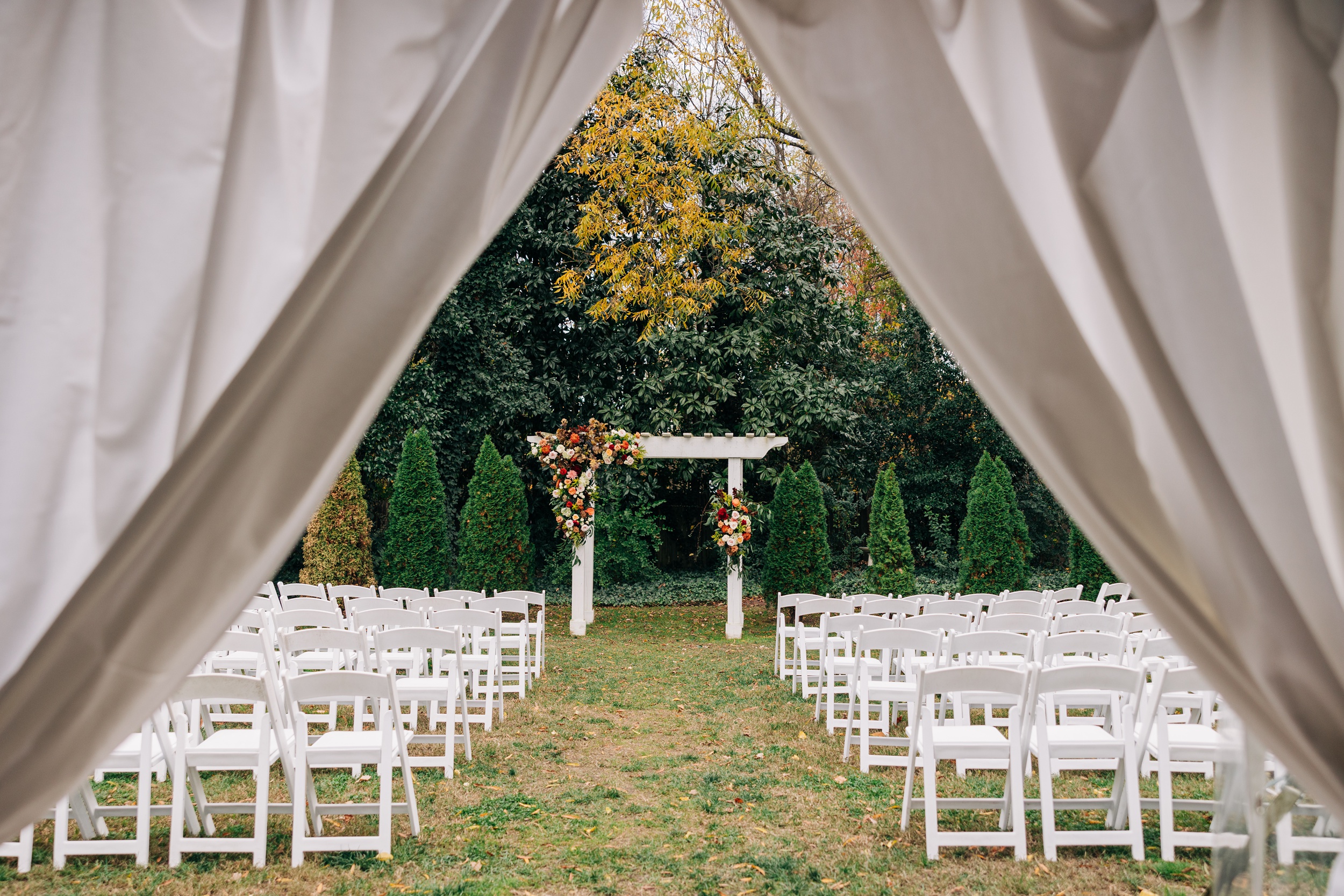 A peek down the aisle of a wedding reception in a garden at The Finch House