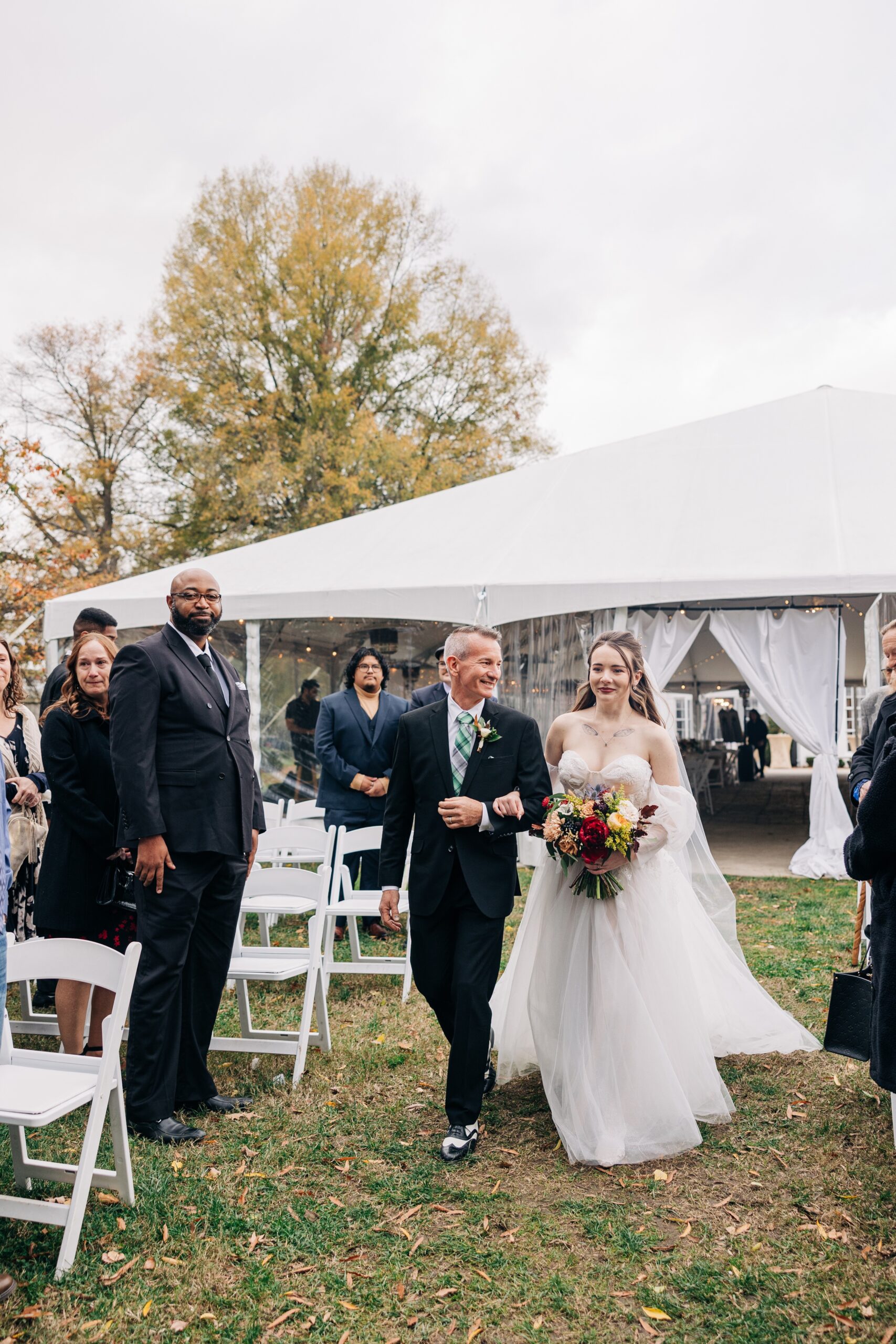 A bride walks down the aisle with dad at her ceremony at The Finch House