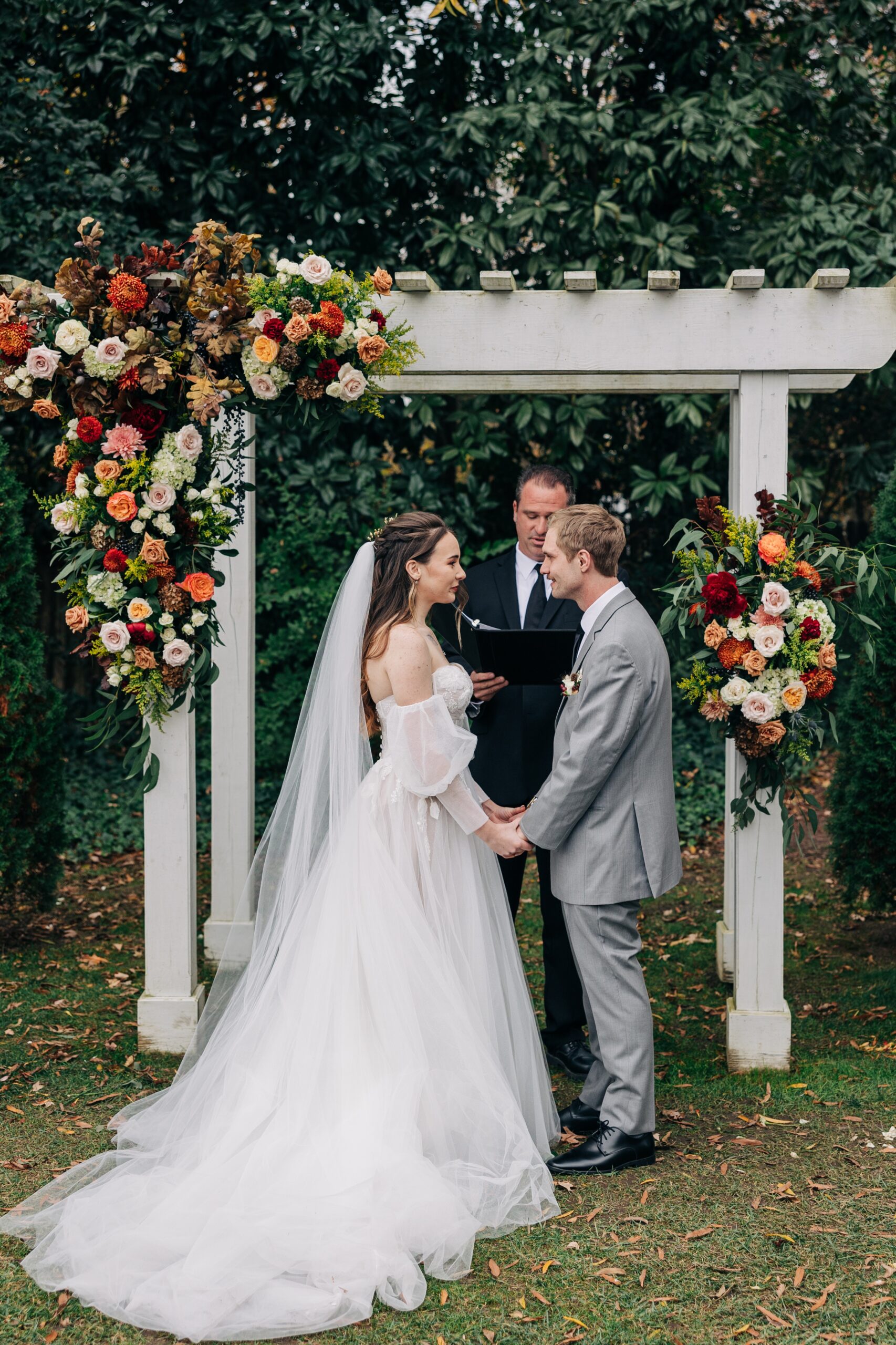 Happy newlyweds smile at each other while holding hands during their ceremony