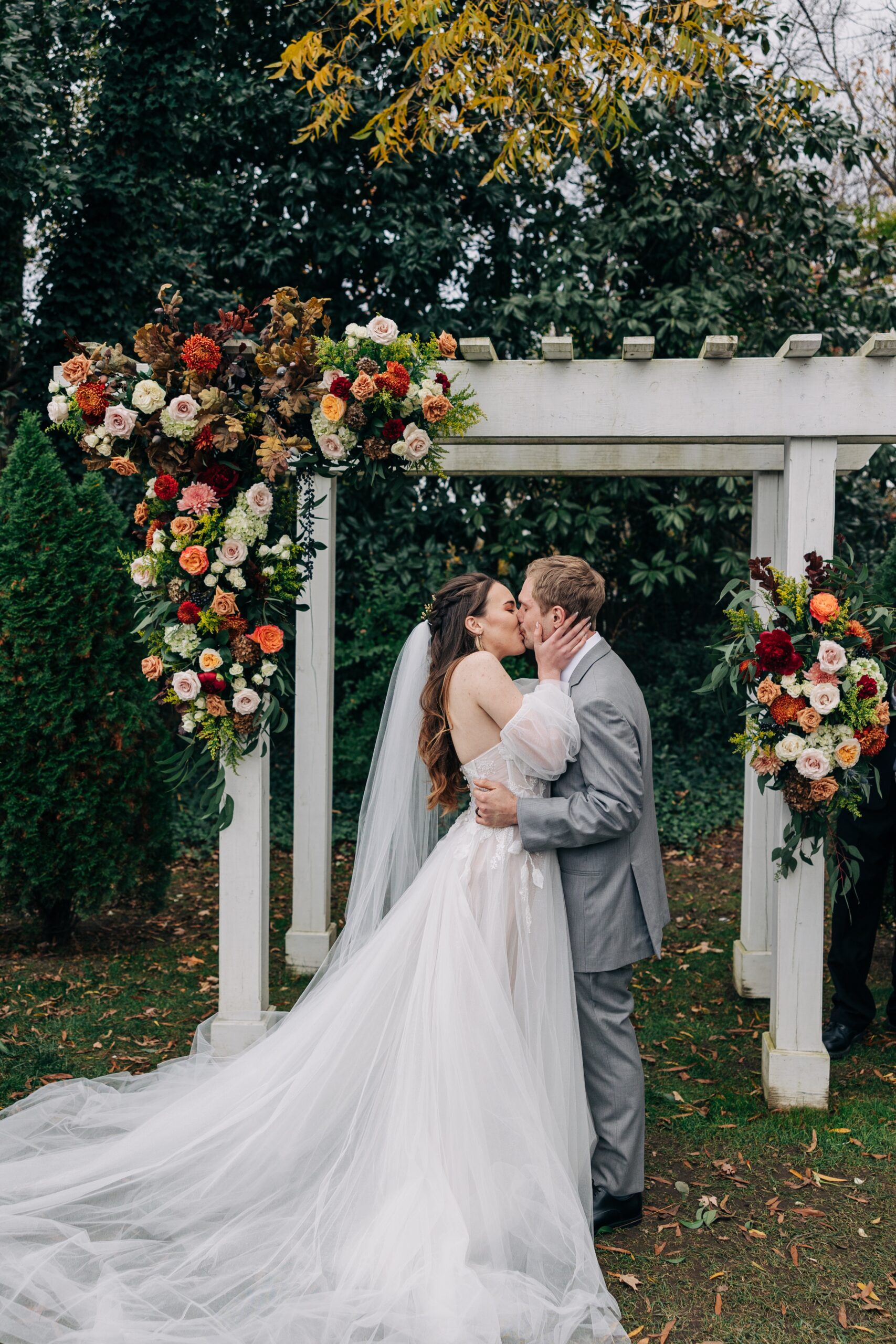 Newlyweds kiss under the floral covered arbor to end their ceremony