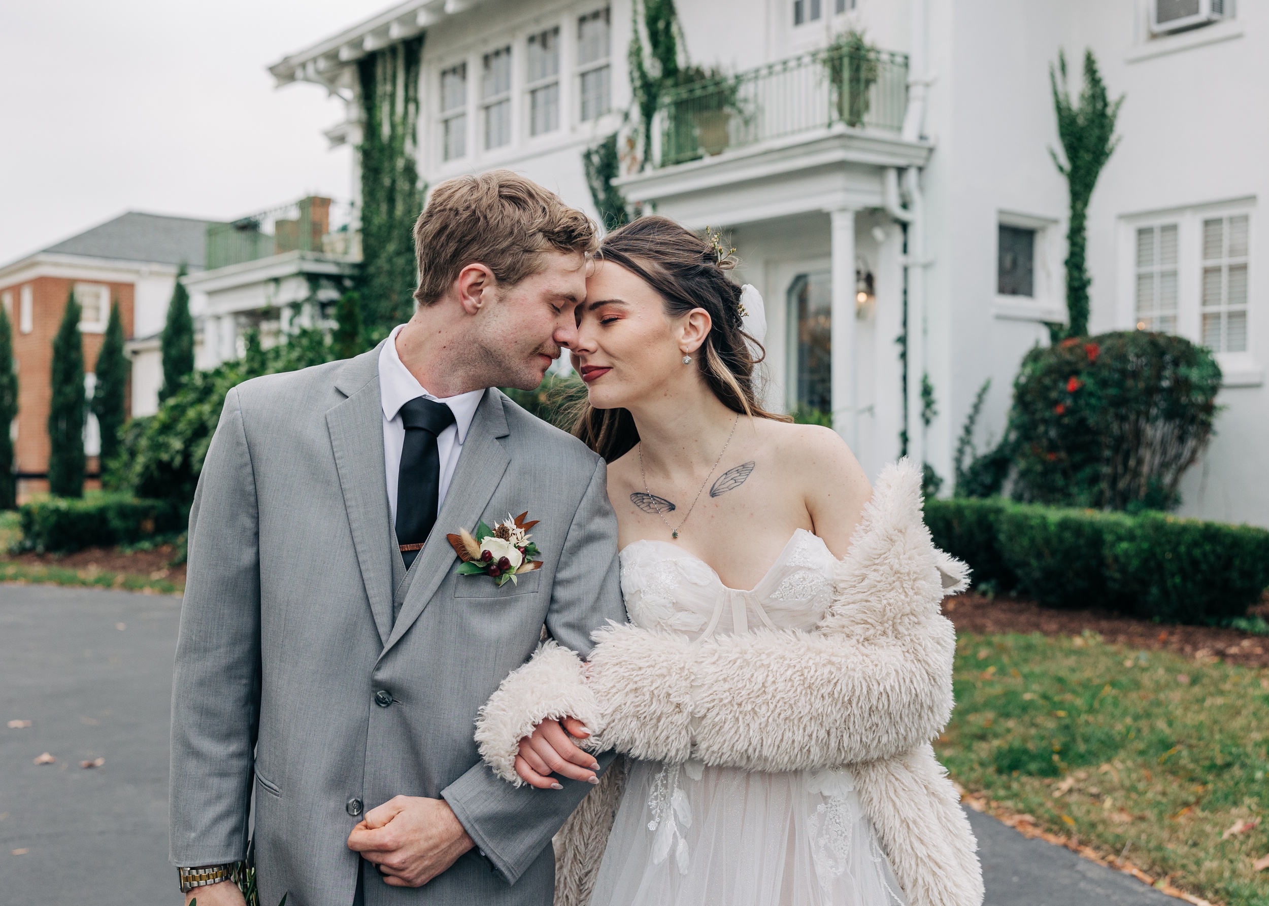 Newlyweds snuggle while walking in the driveway of The Finch House