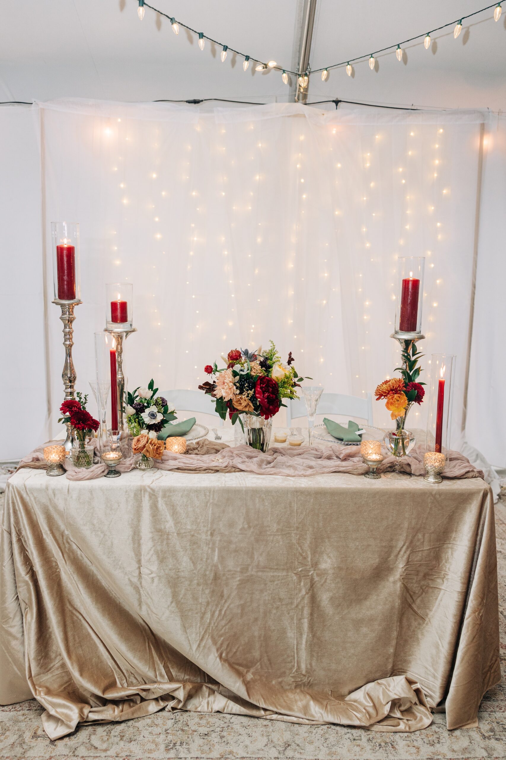 Details of a wedding head table with gold linen and red candles