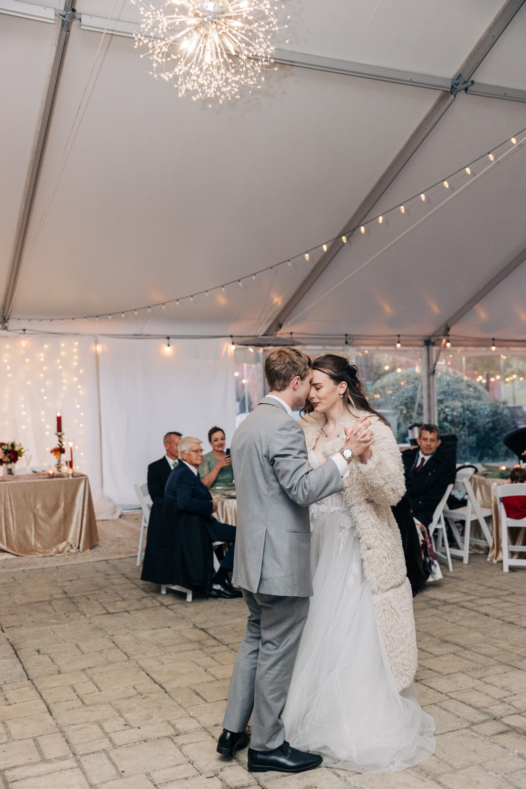 Newlyweds dance while touching foreheads under a tent at their reception