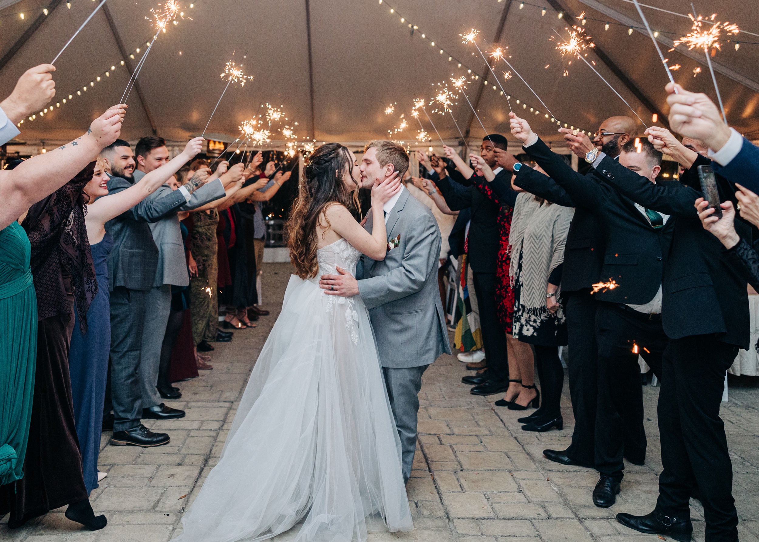 Newlywed kiss under an arch of sparklers held by guests at The Finch House