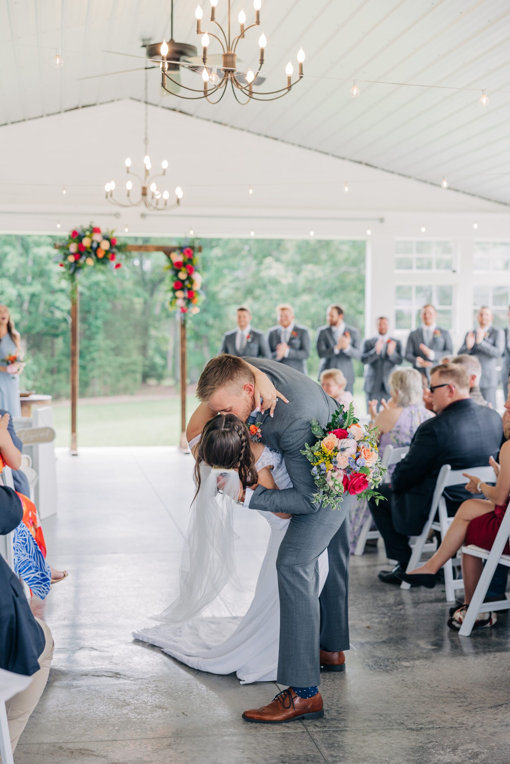 A groom dips his bride in the aisle for a kiss after their ceremony