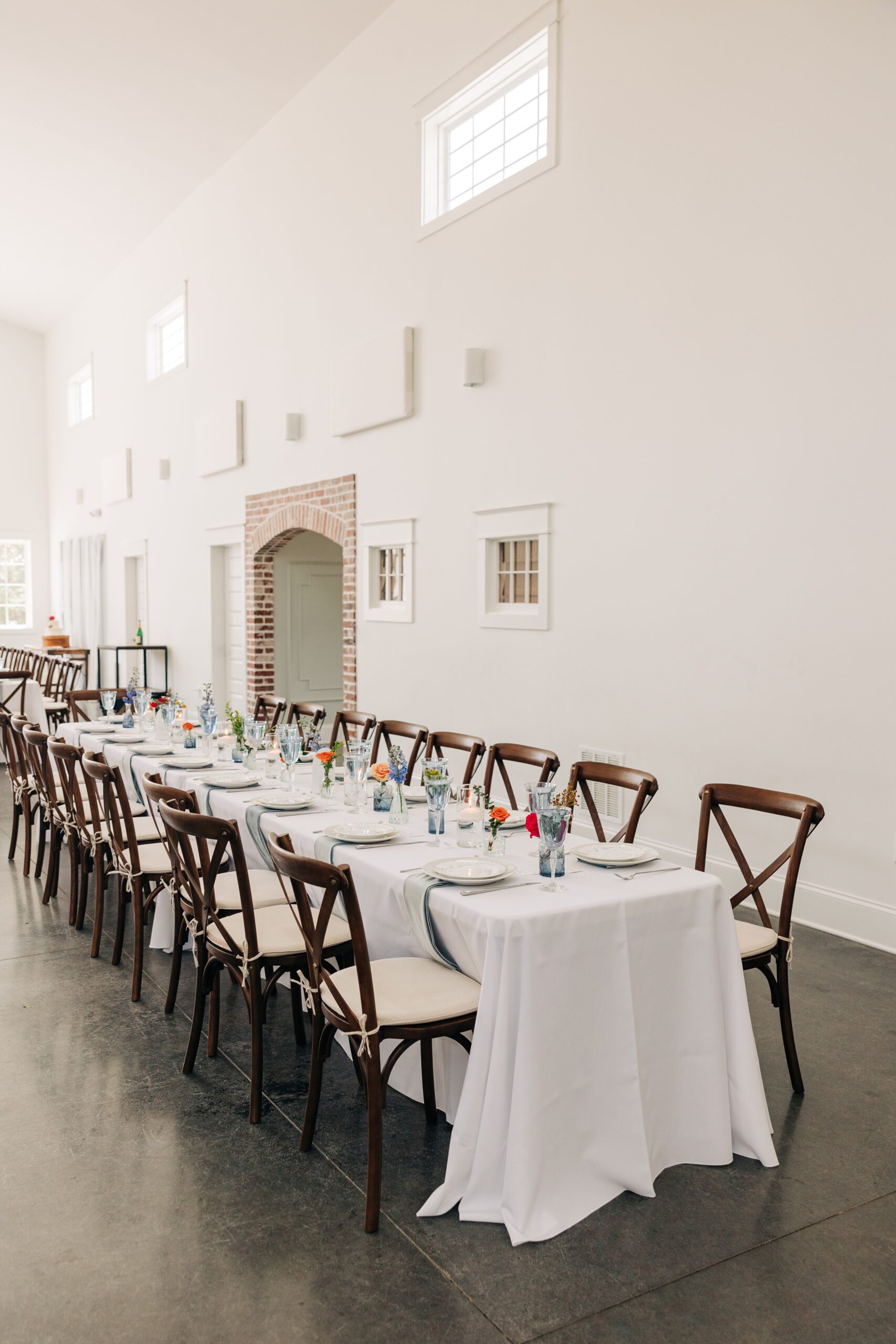 Details of a long reception table set up with white linen at The Ivory Barn