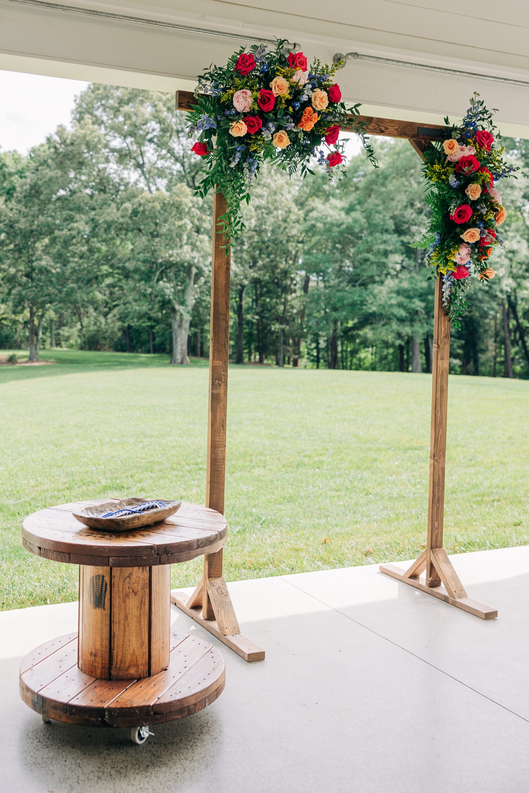 Details of a wooden wedding arbor with colorful florals for an open air ceremony at The Ivory Barn