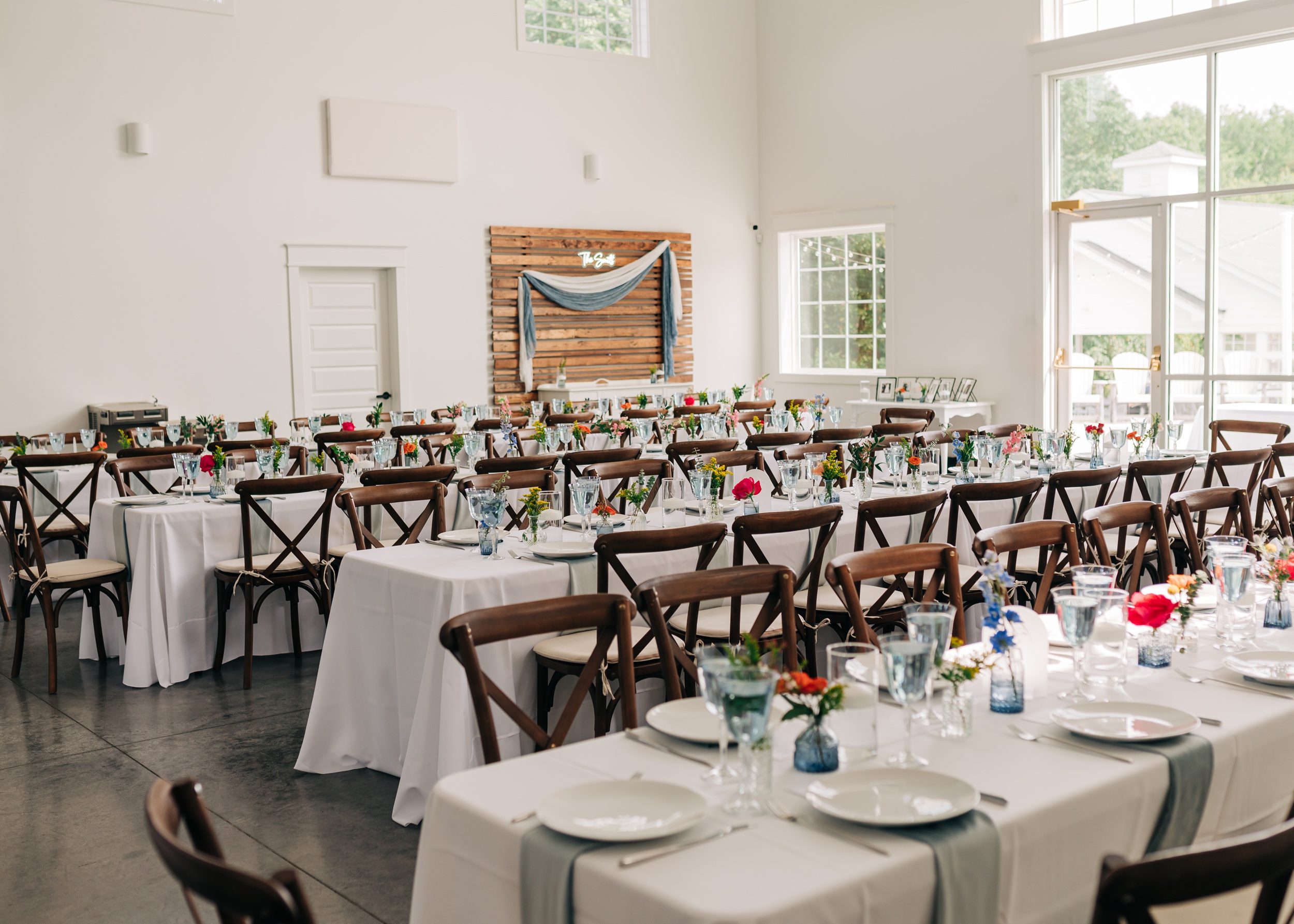 Details of a wedding reception set up at The Ivory Barn with wood chairs and white linens