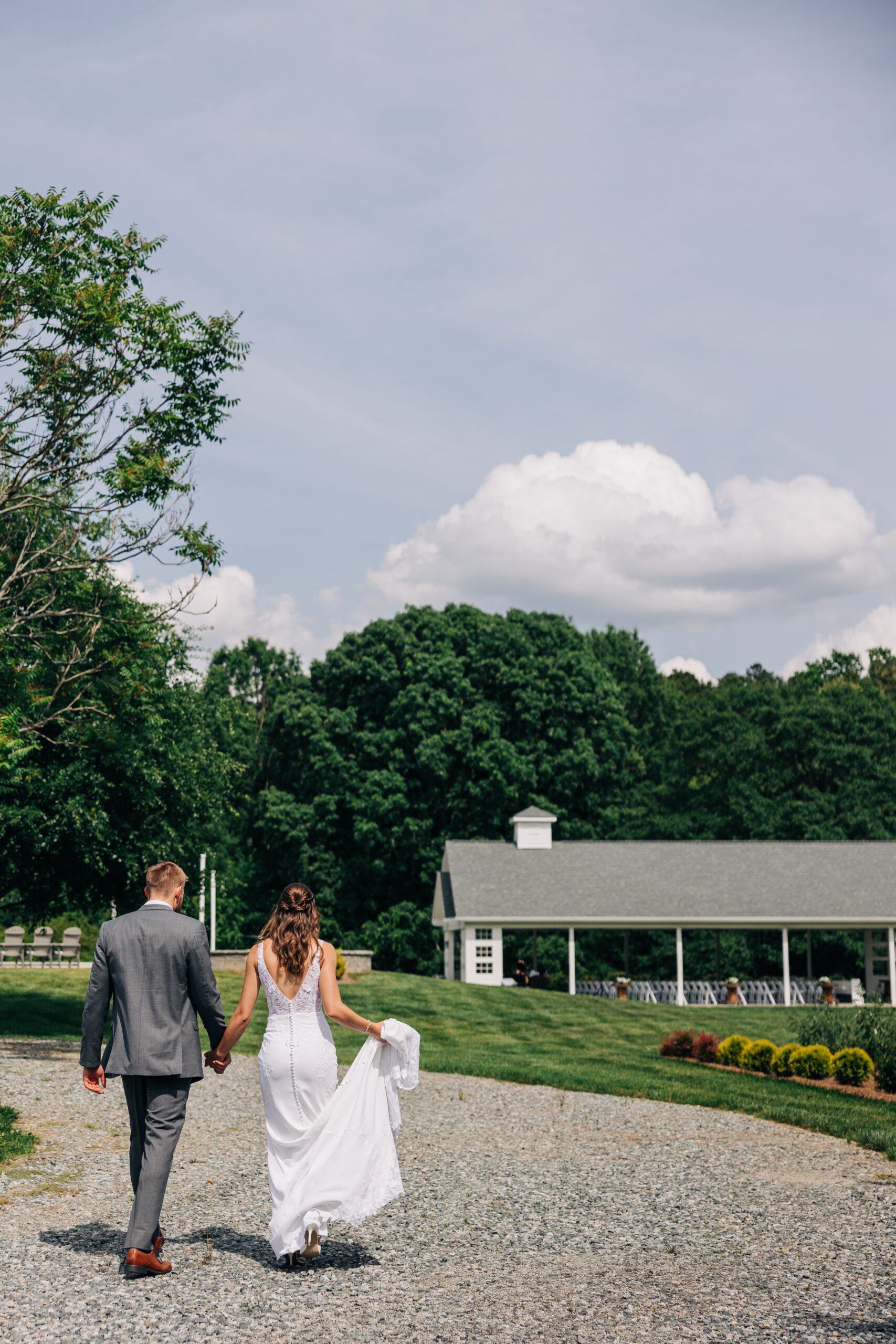 Newlyweds walk the gardens of The Ivory Barn while holding hands and the train