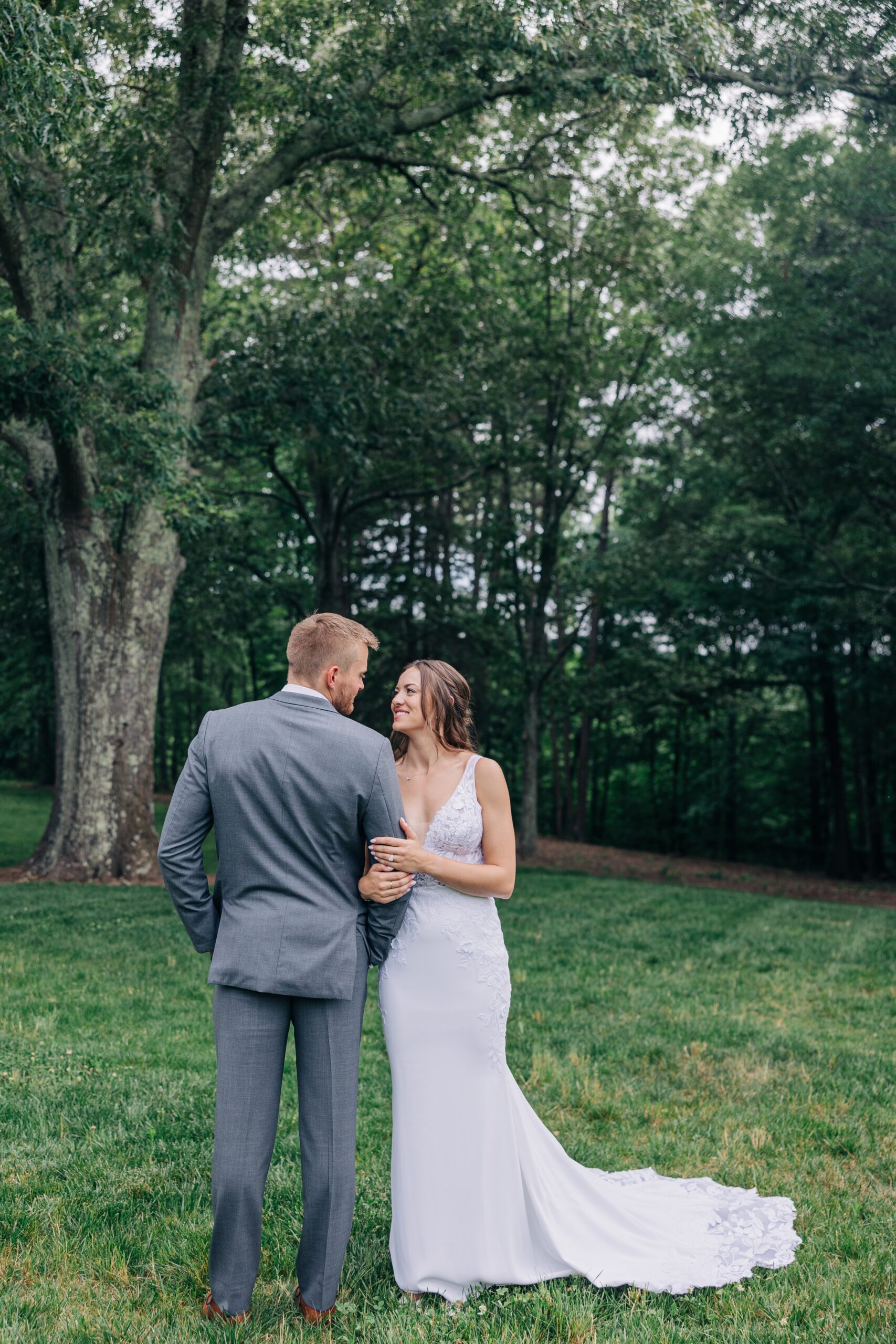 A bride hangs on her groom's arm while they explore the grounds of their venue