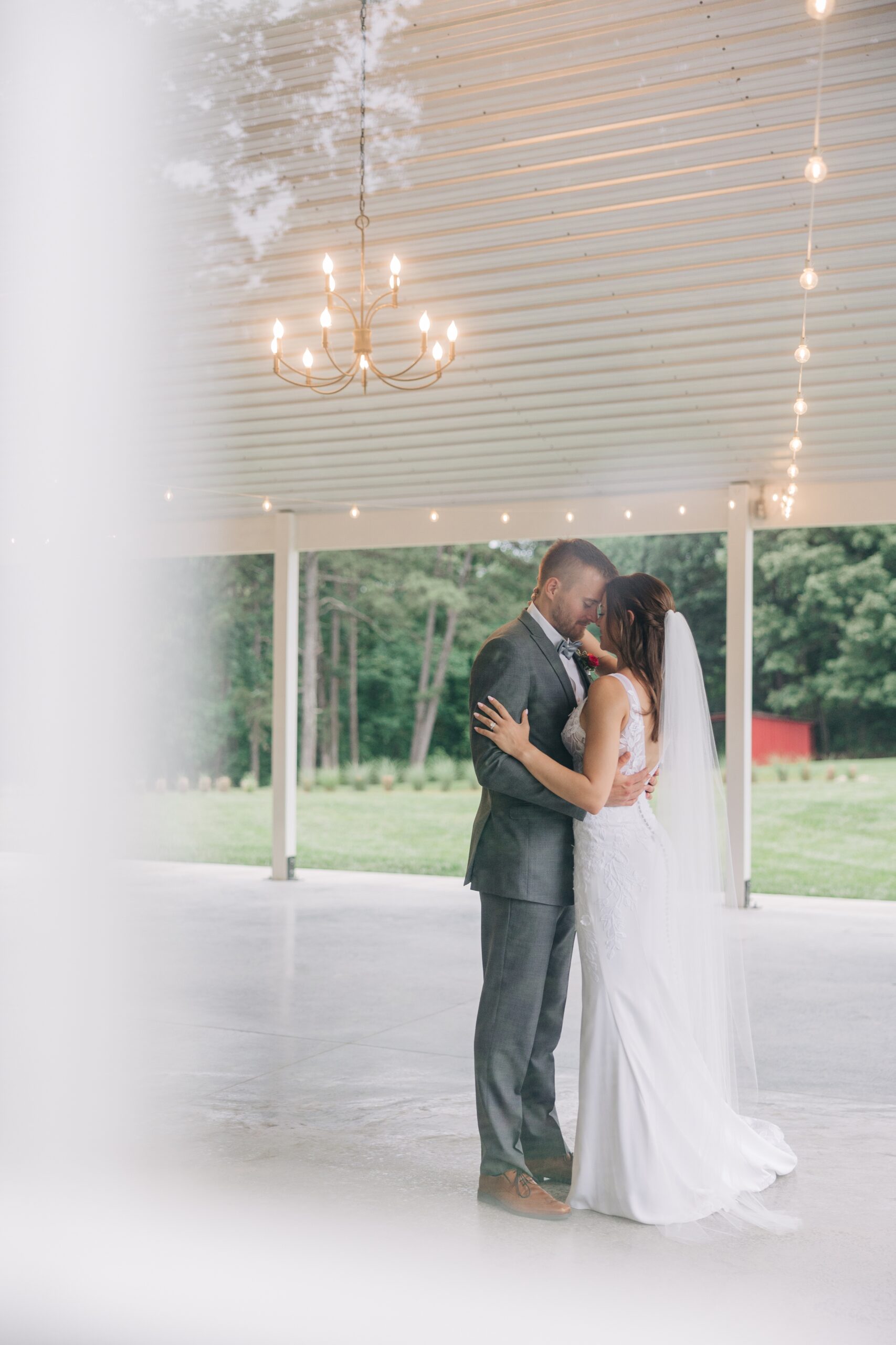 Newlyweds dance under a chandelier touching foreheads