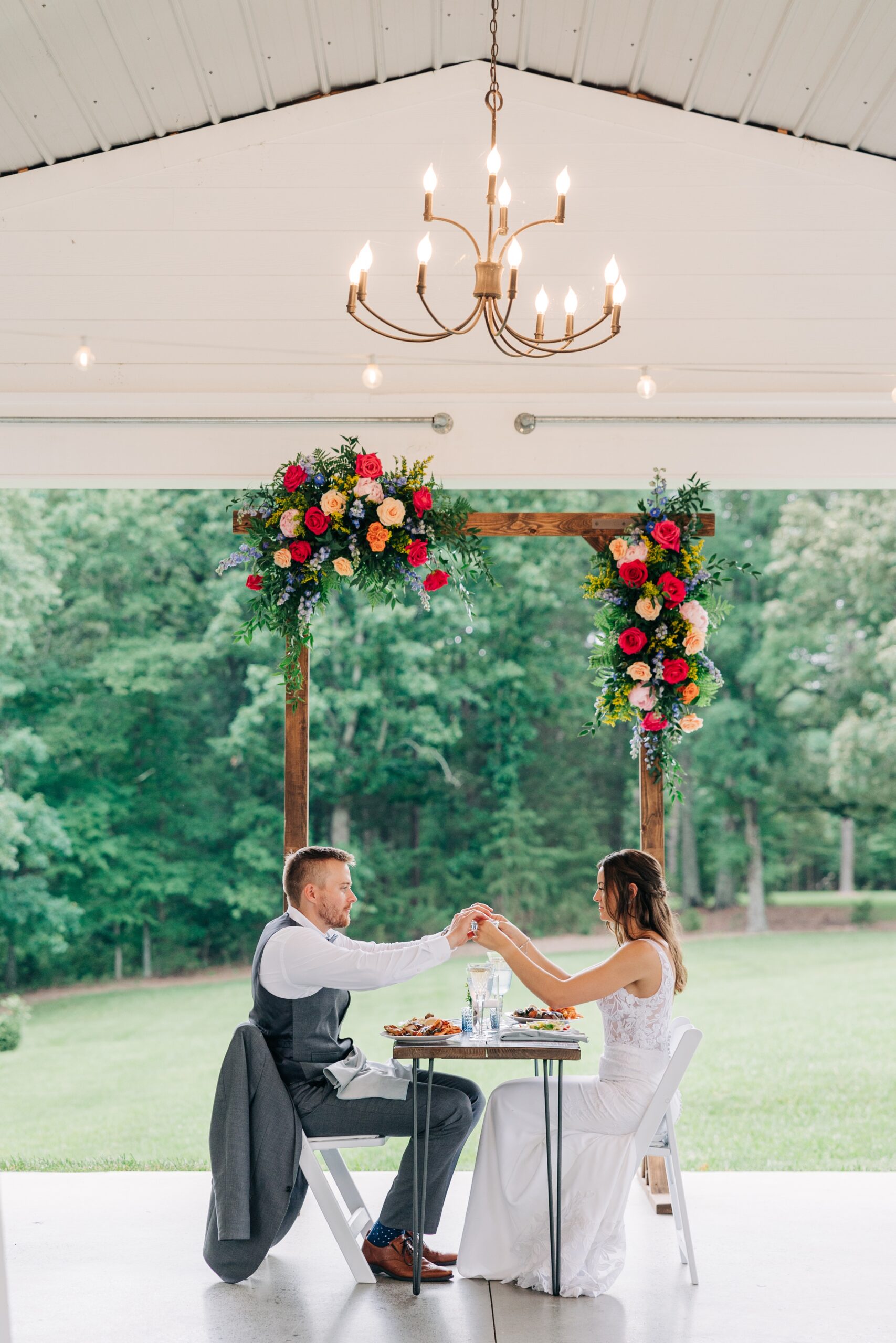 Newlyweds hold hands over a private table before eating at The Ivory Barn