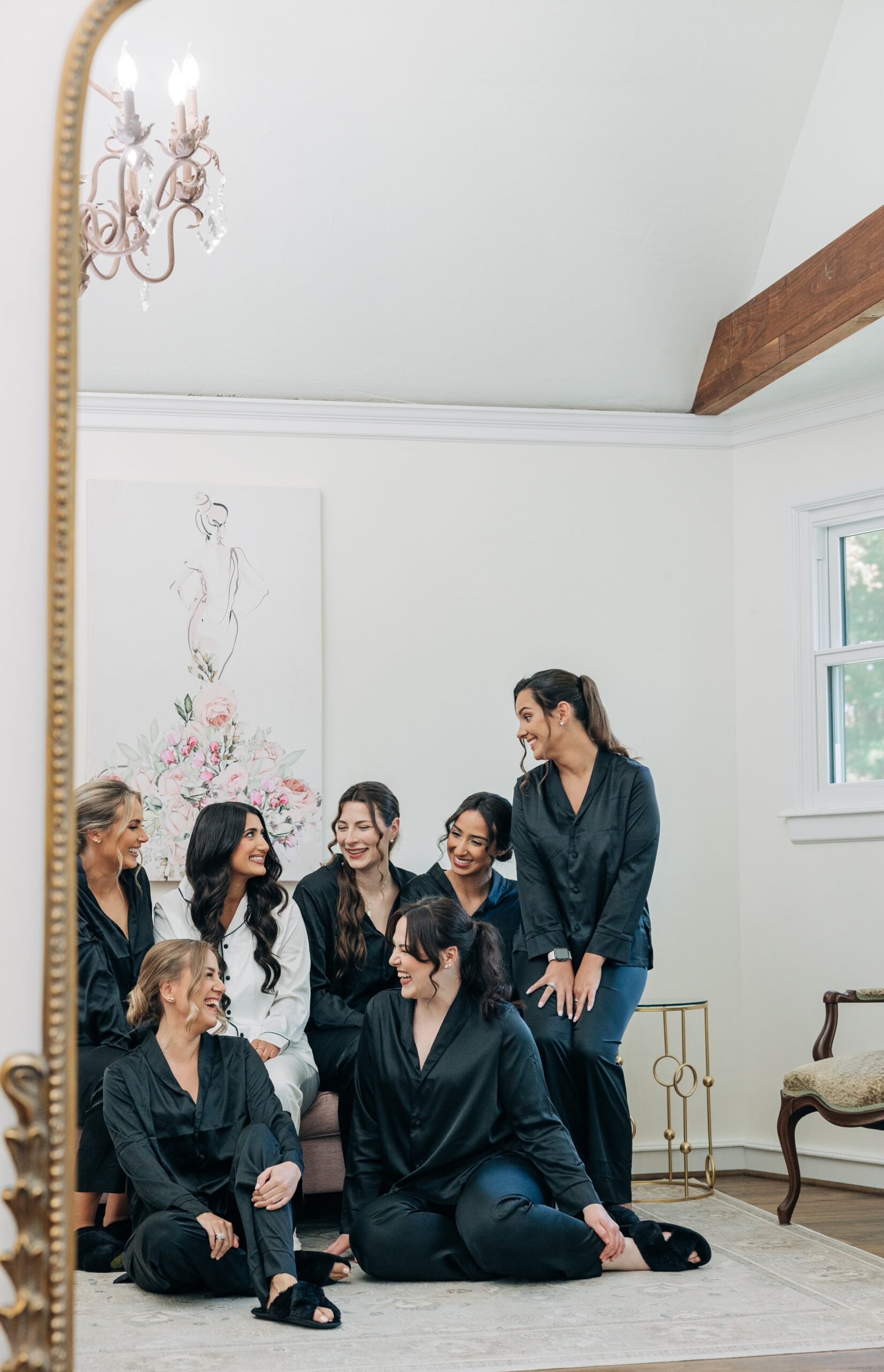 A bride sits on a couch in pajamas with her bridesmaids around her