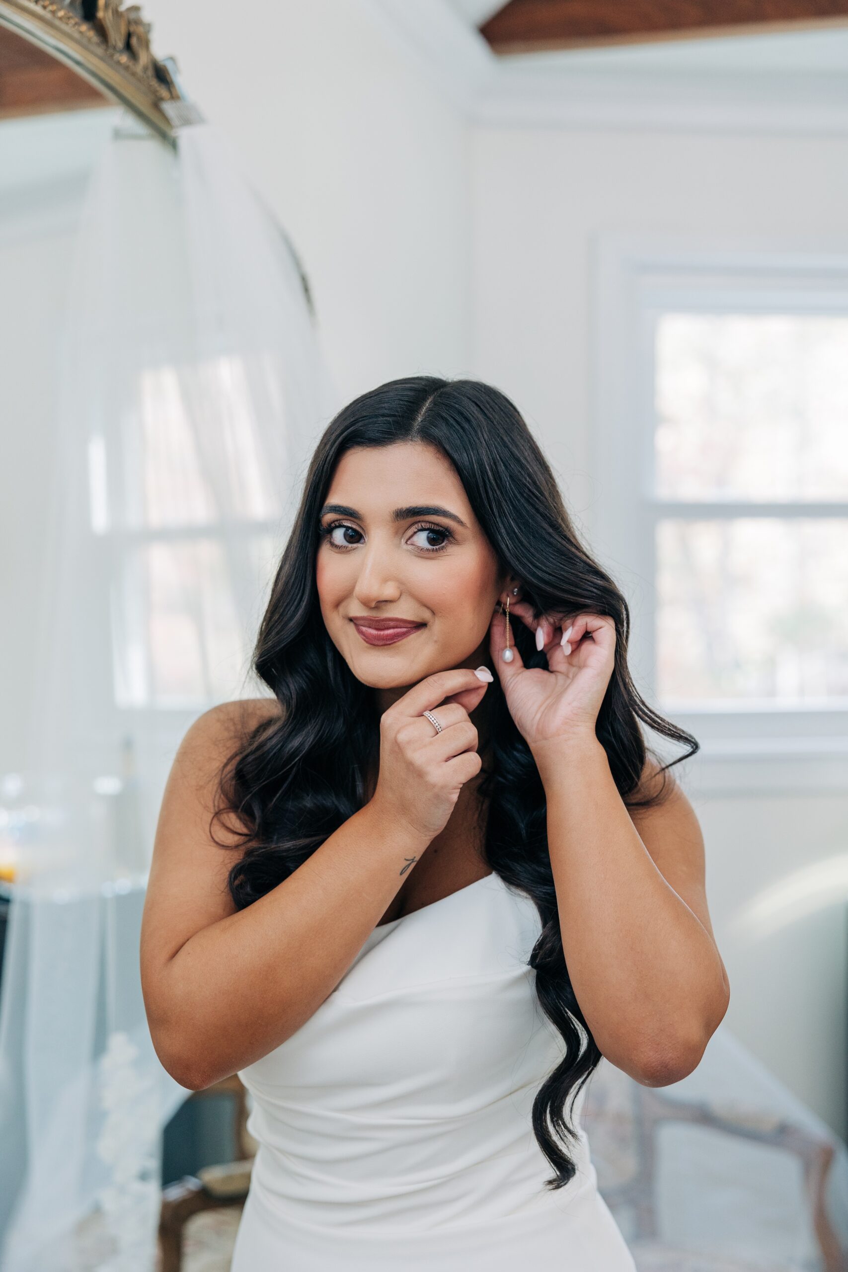 A bride puts on her earrings while getting ready for her covington gardens wedding