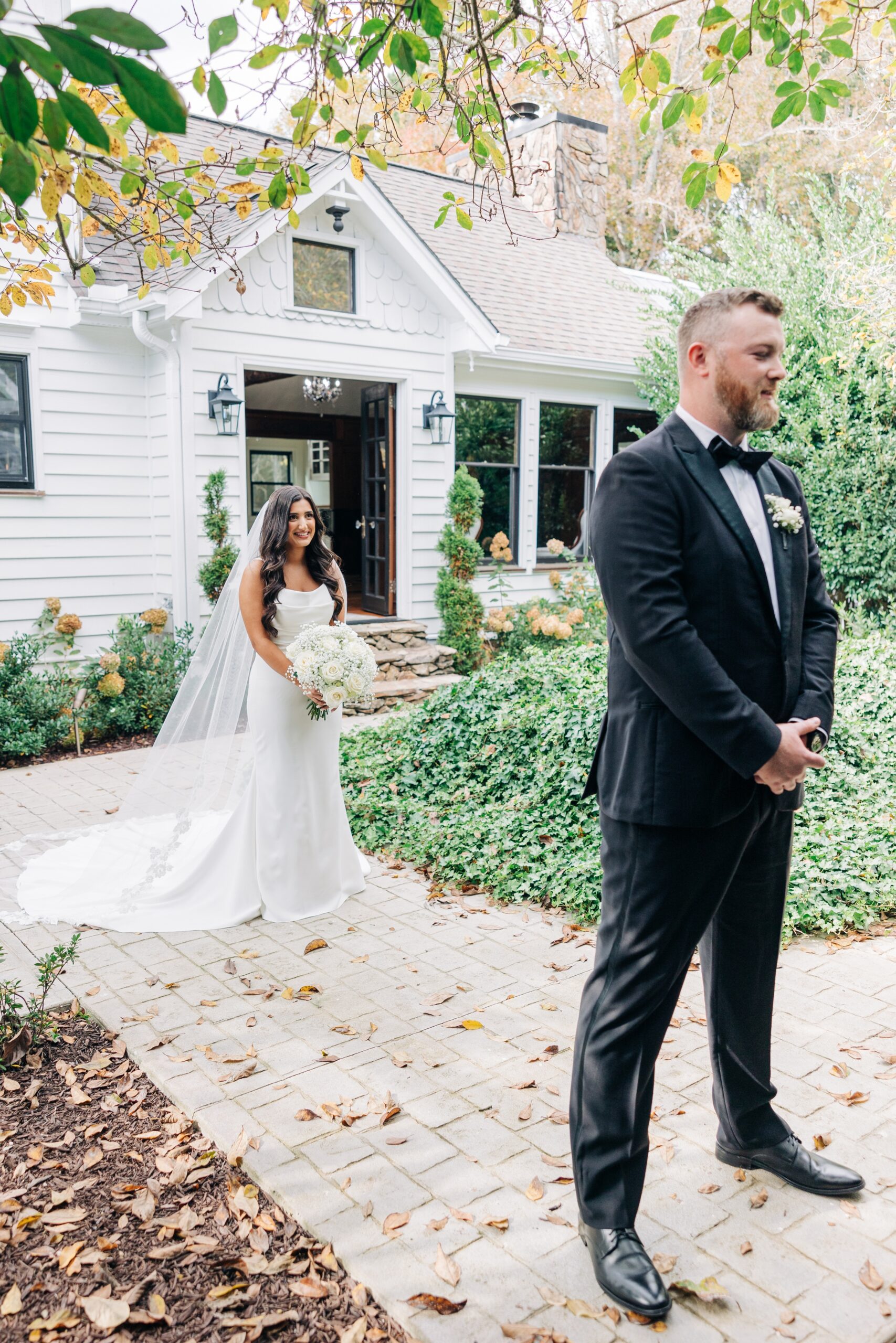 A groom in a black tux waits for his bride to do a covington gardens first look