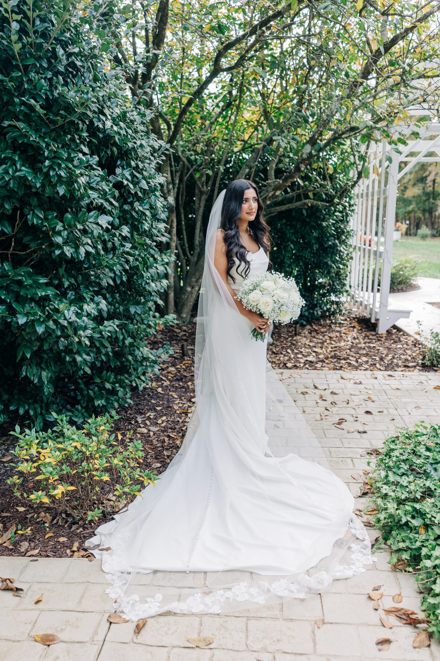 A bride walks through the gardens holding her bouquet