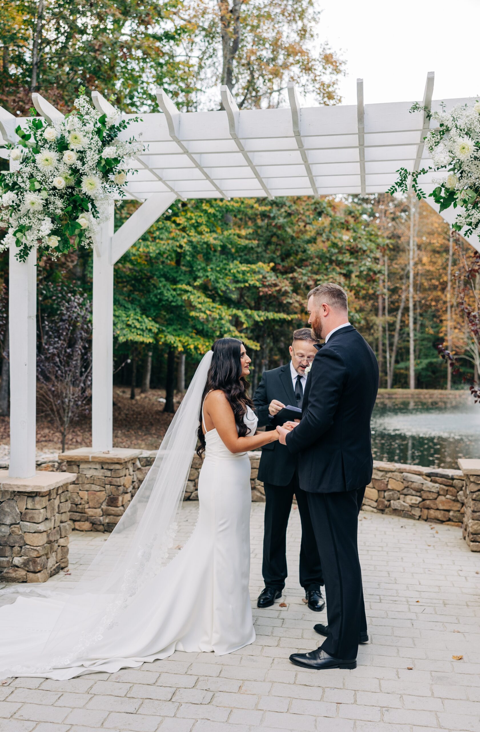 A bride and groom hold hands under the ceremony pergola at covington gardens