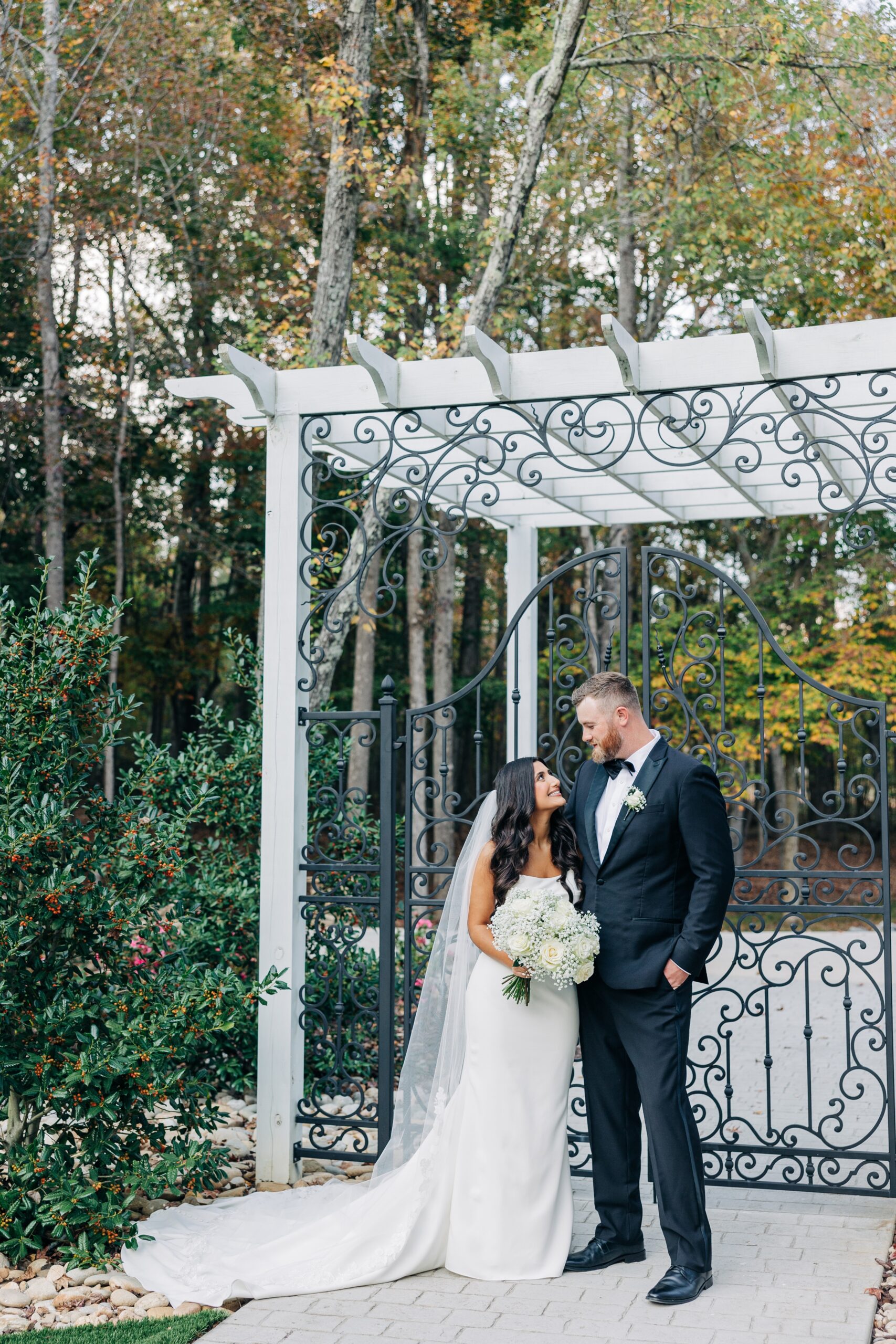 Newlyweds snuggle and smile at each other in front of an iron gate at their covington gardens wedding