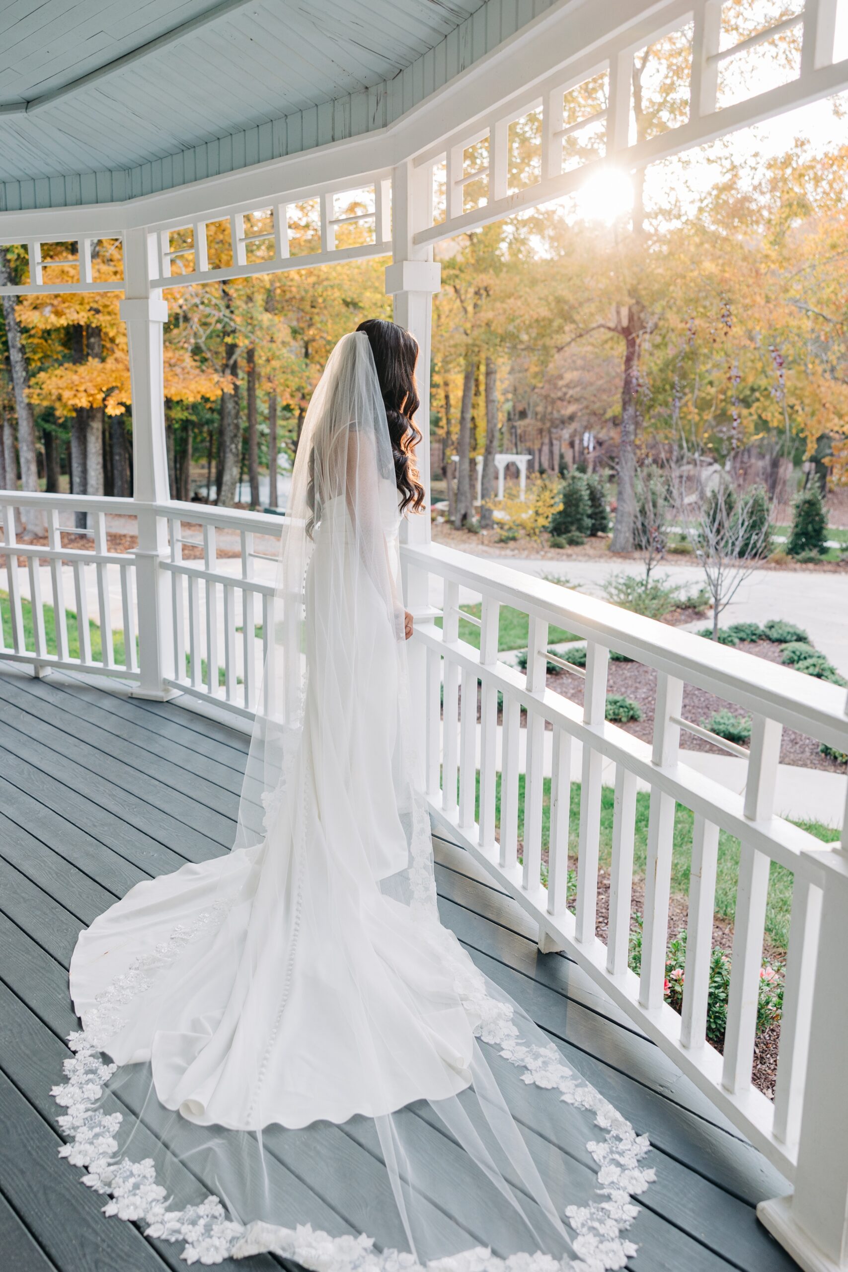 A bride looks off the covington gardens porch at sunset