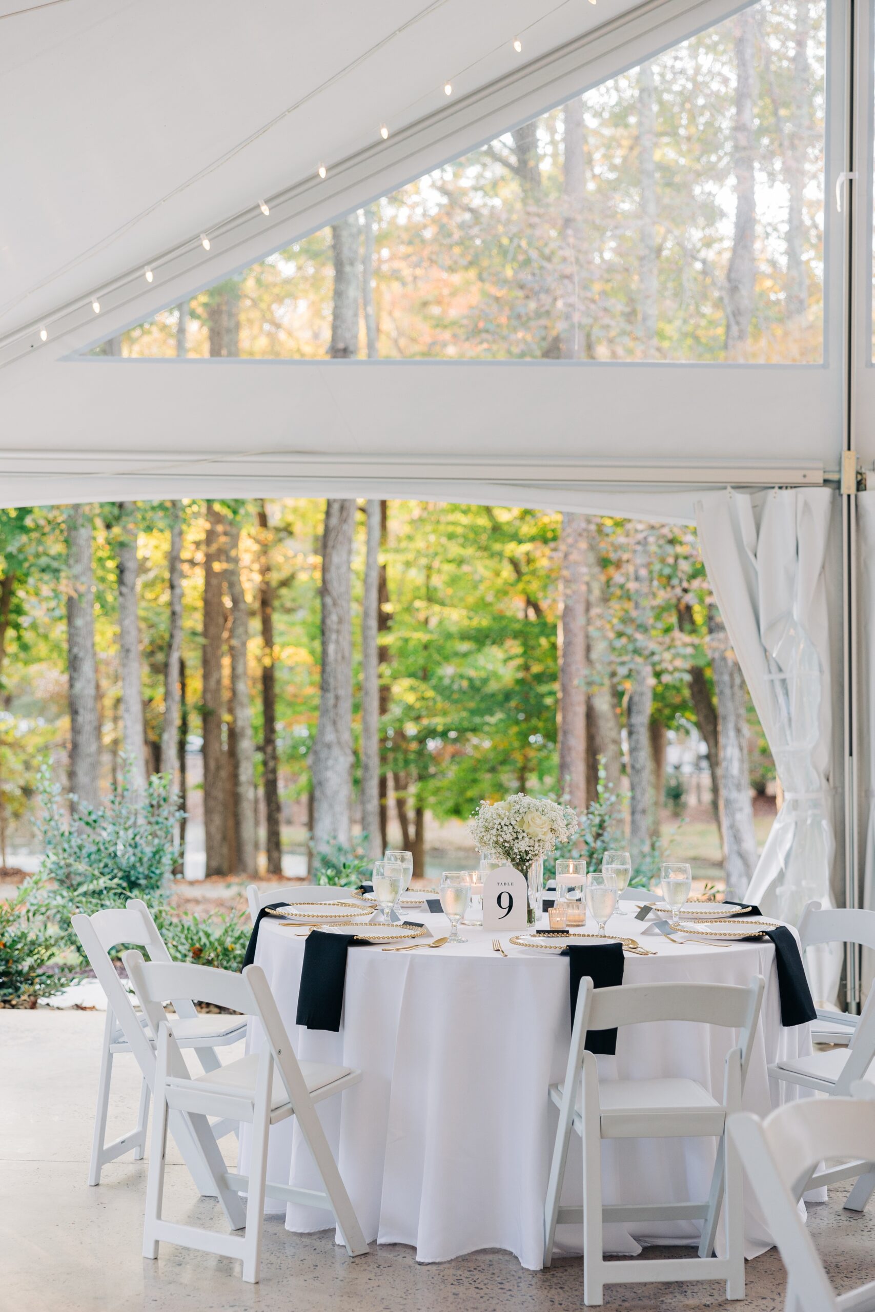 A covington gardens outdoor wedding reception table set up with white linen and black napkin