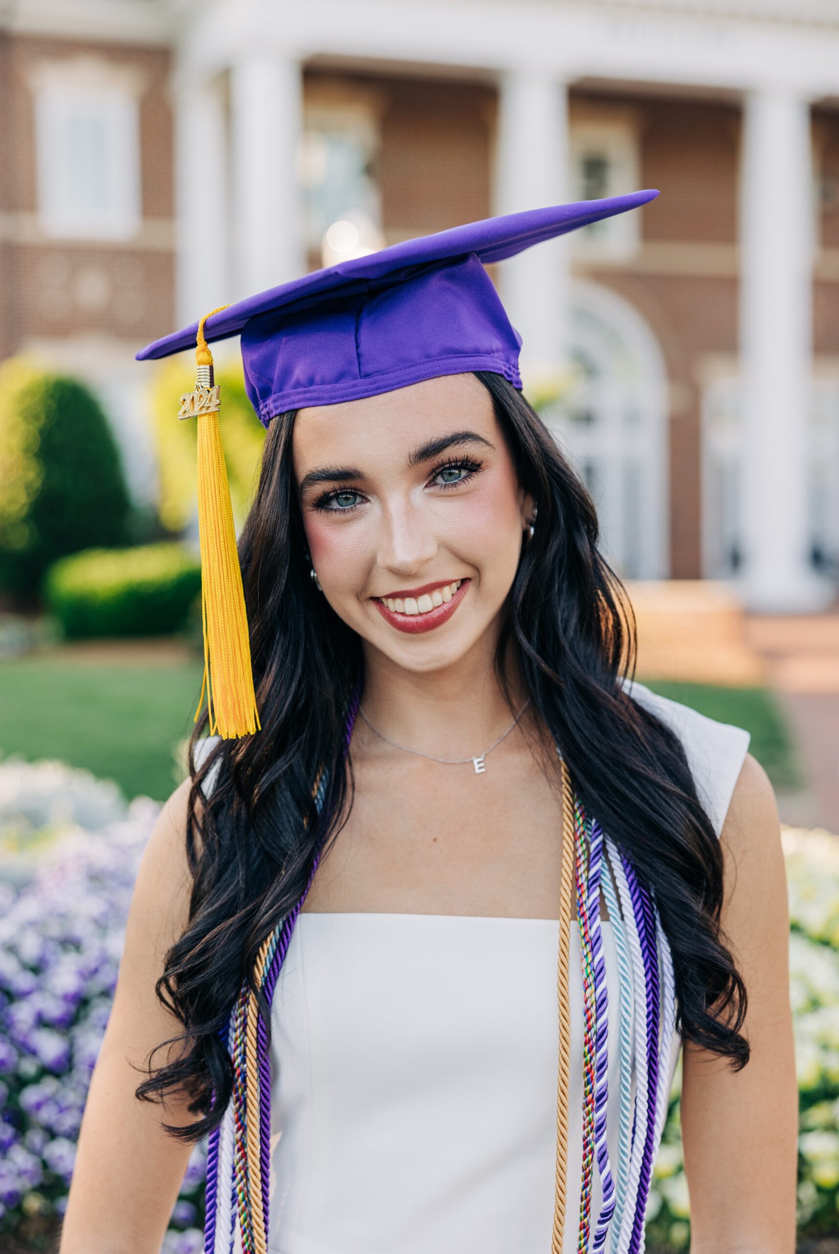 A happy graduate smiles in her purple cap and white dress