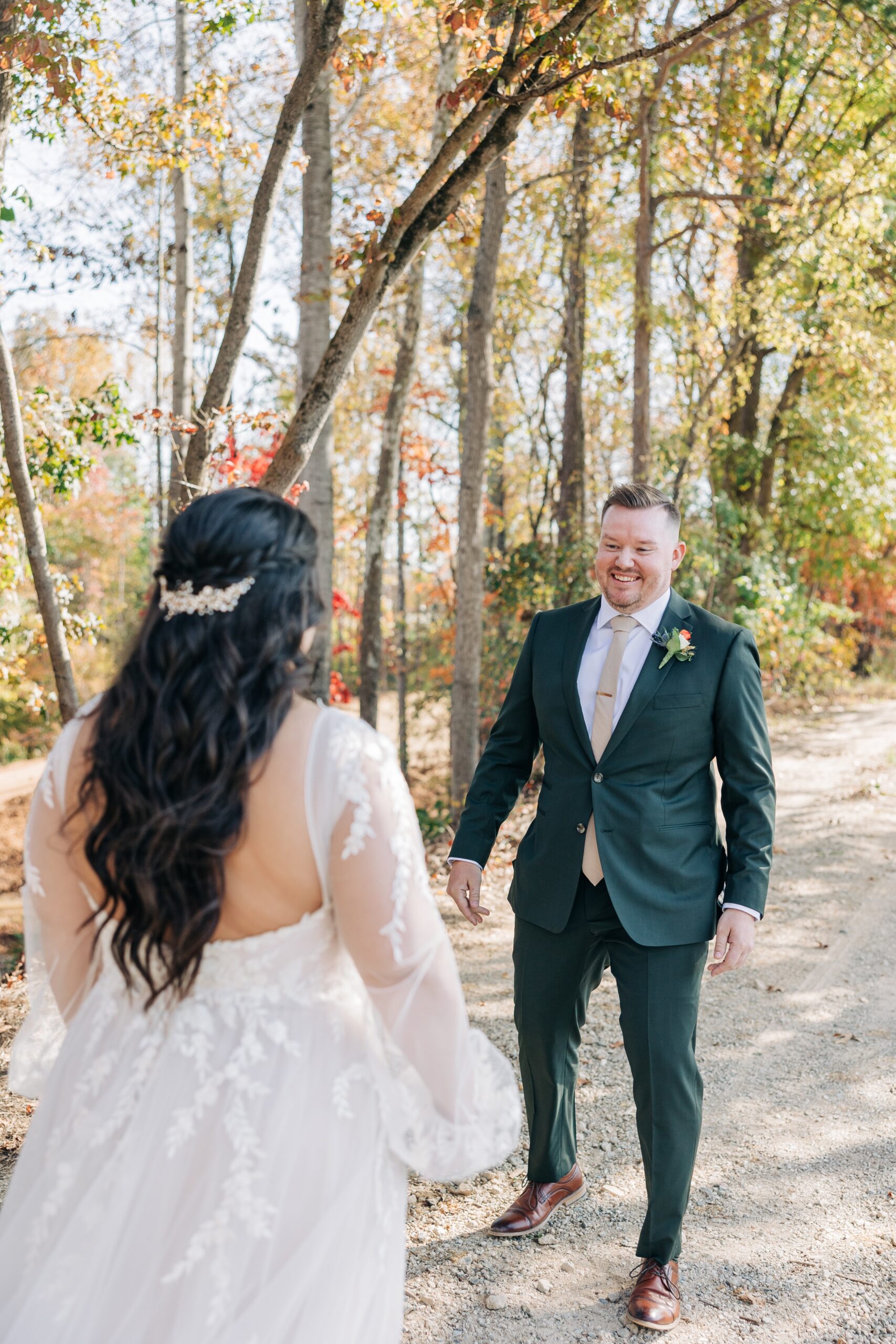 A groom smiles big during his first look in a forest