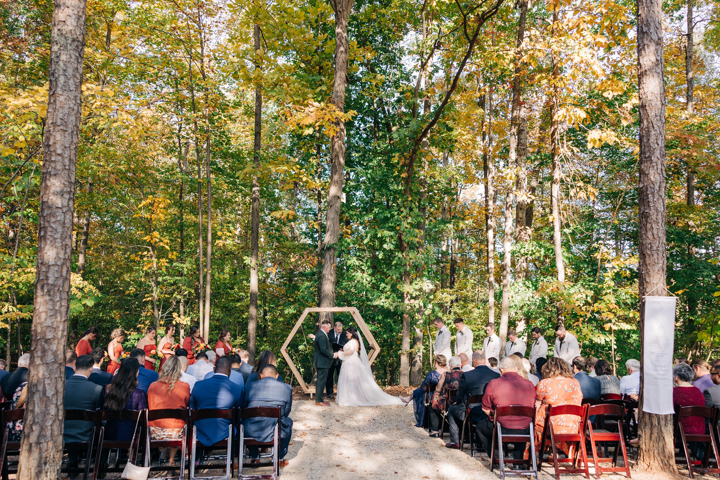 Bride and groom hold hands during their ceremony in the forest at splendor pond flower farm