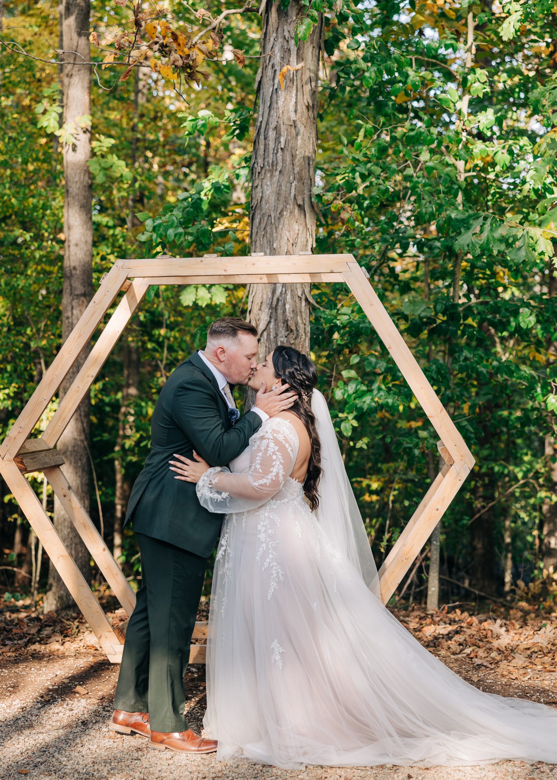 Newlyweds kiss in front of wooden hexagon ceremony altar at splendor pond flower farm