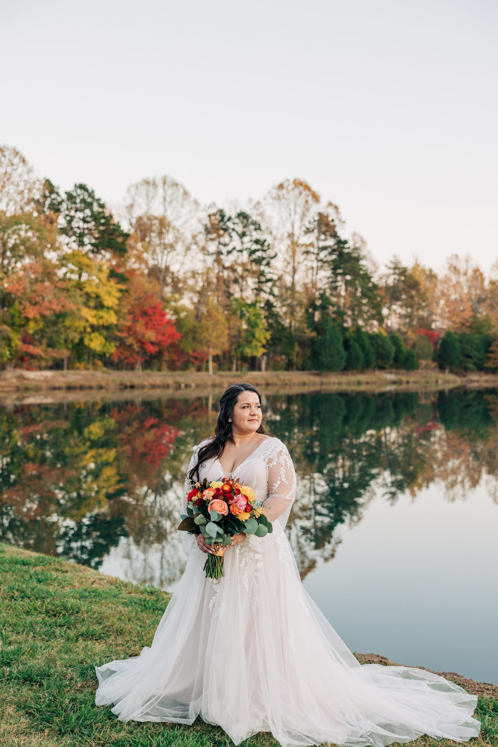 A bride smiles over her shoulder while standing by the water at splendor pond flower farm