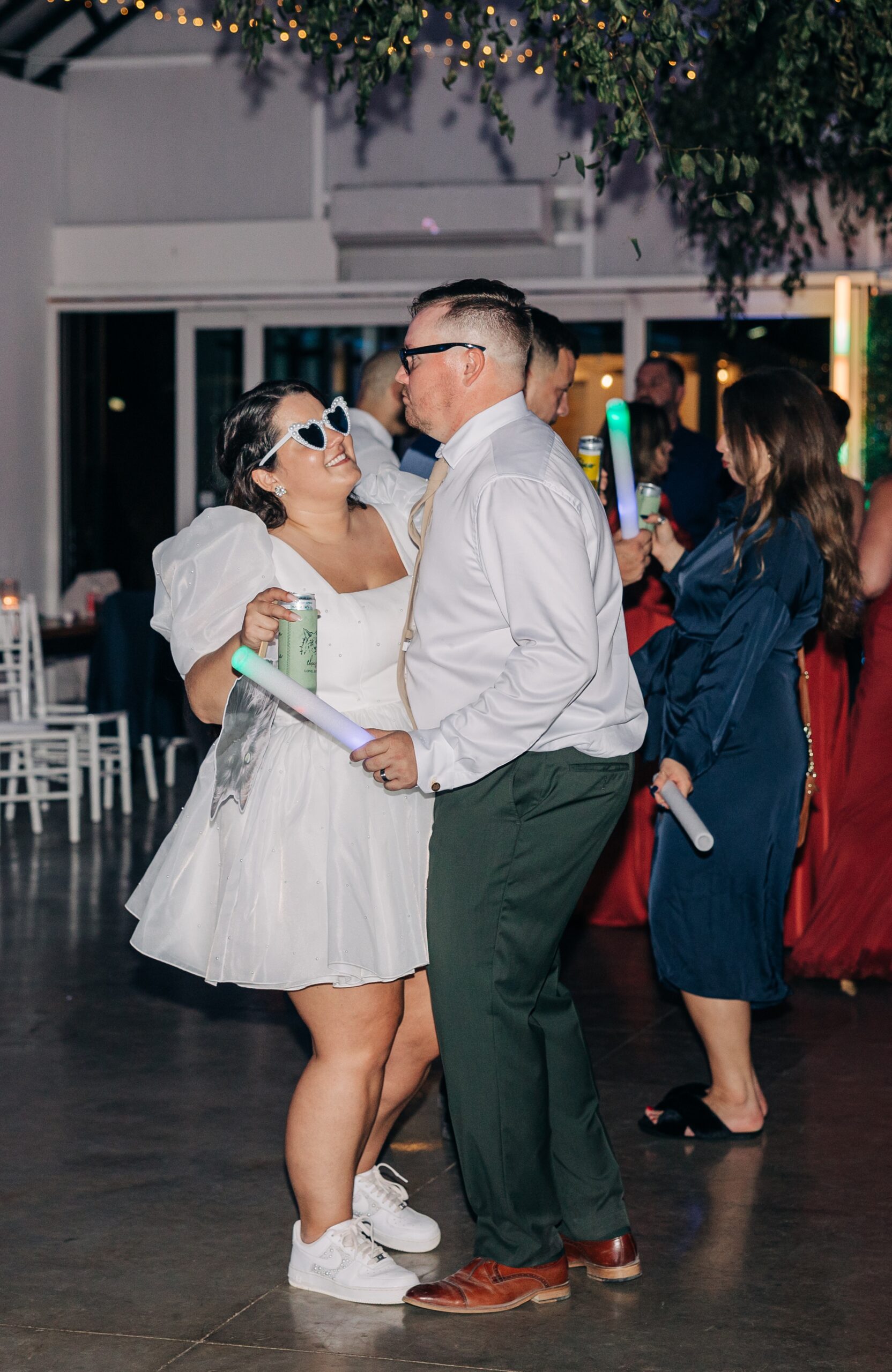 Newlyweds dance with glow sticks and drinks on the dance floor