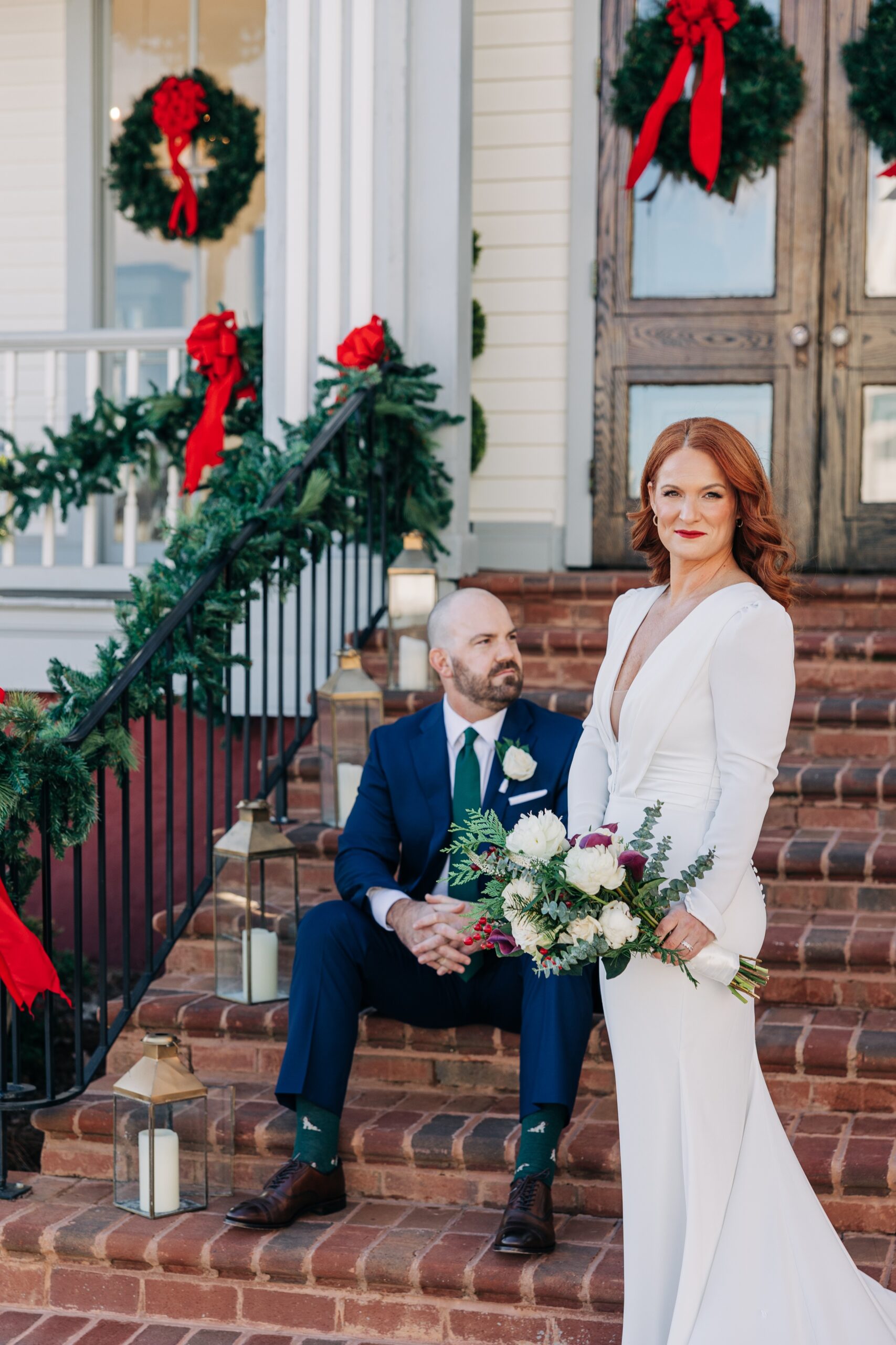 Newlyweds sit and stand on the christmas themed porch and stairs at the crest winston-salem