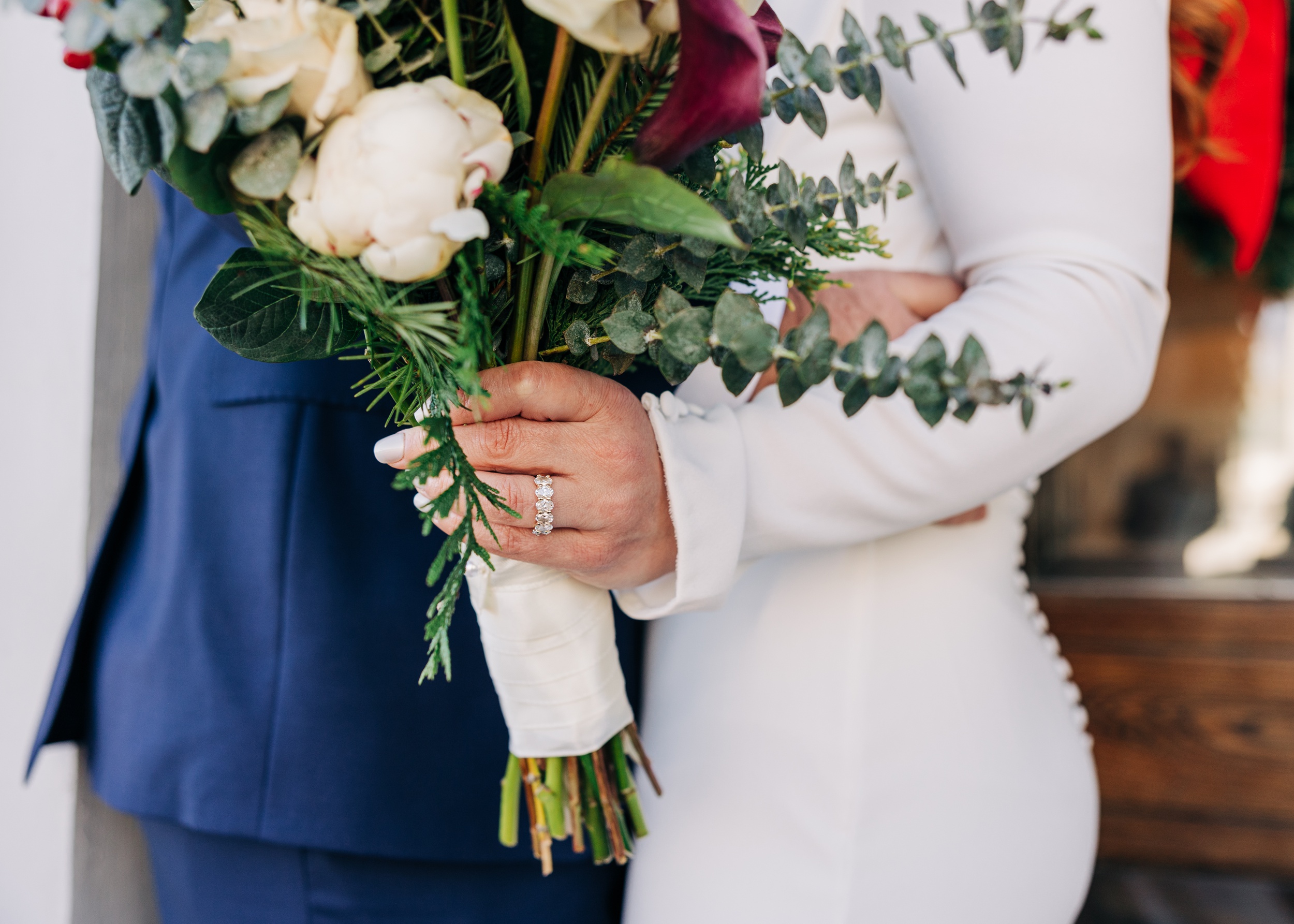 Details of a bride's hand holding a bouquet with her ring