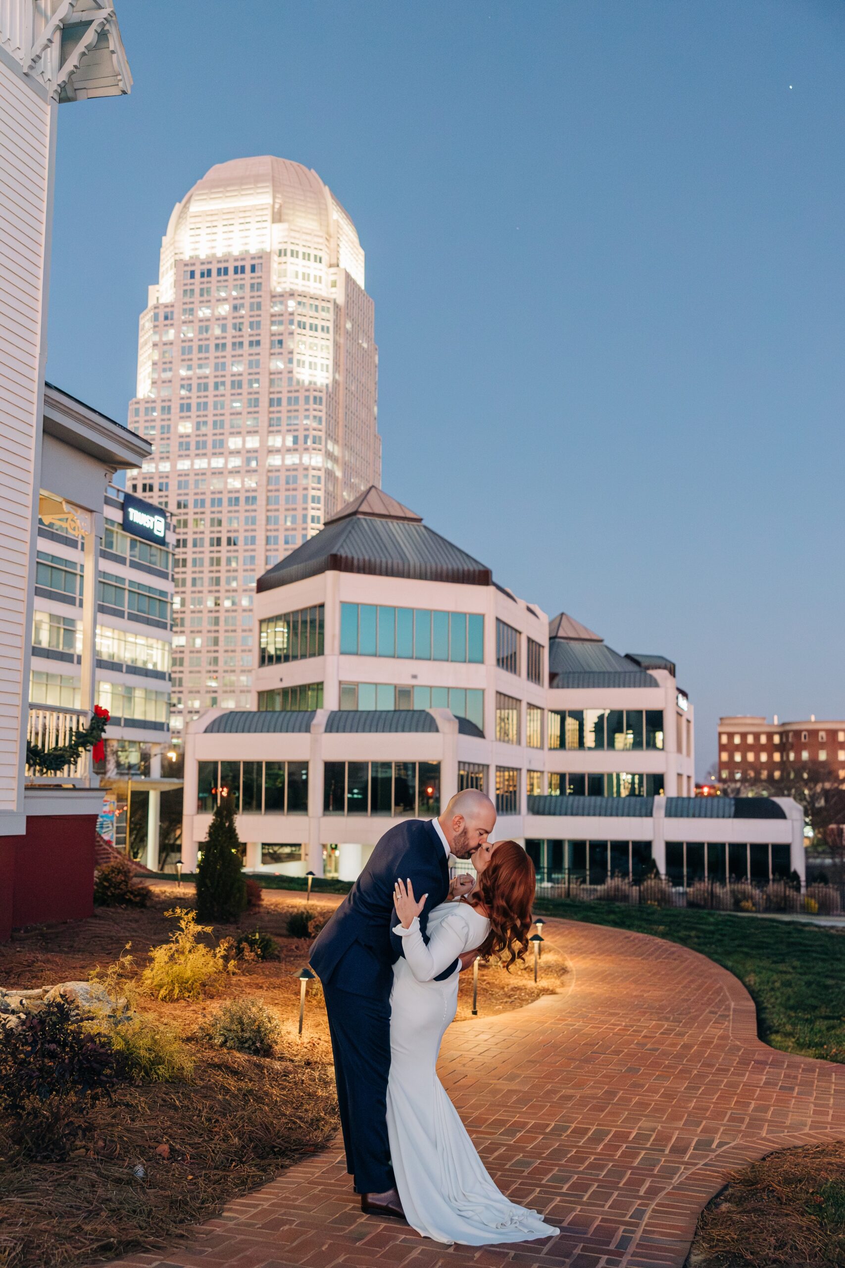 Newlyweds kiss on a brick sidewalk at the crest winston-salem in downtown