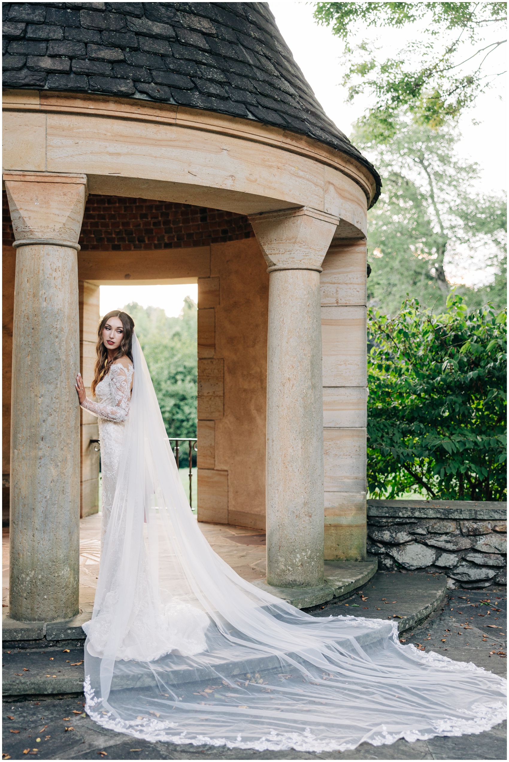A bride leans on a gazebo column with her train extended behind her