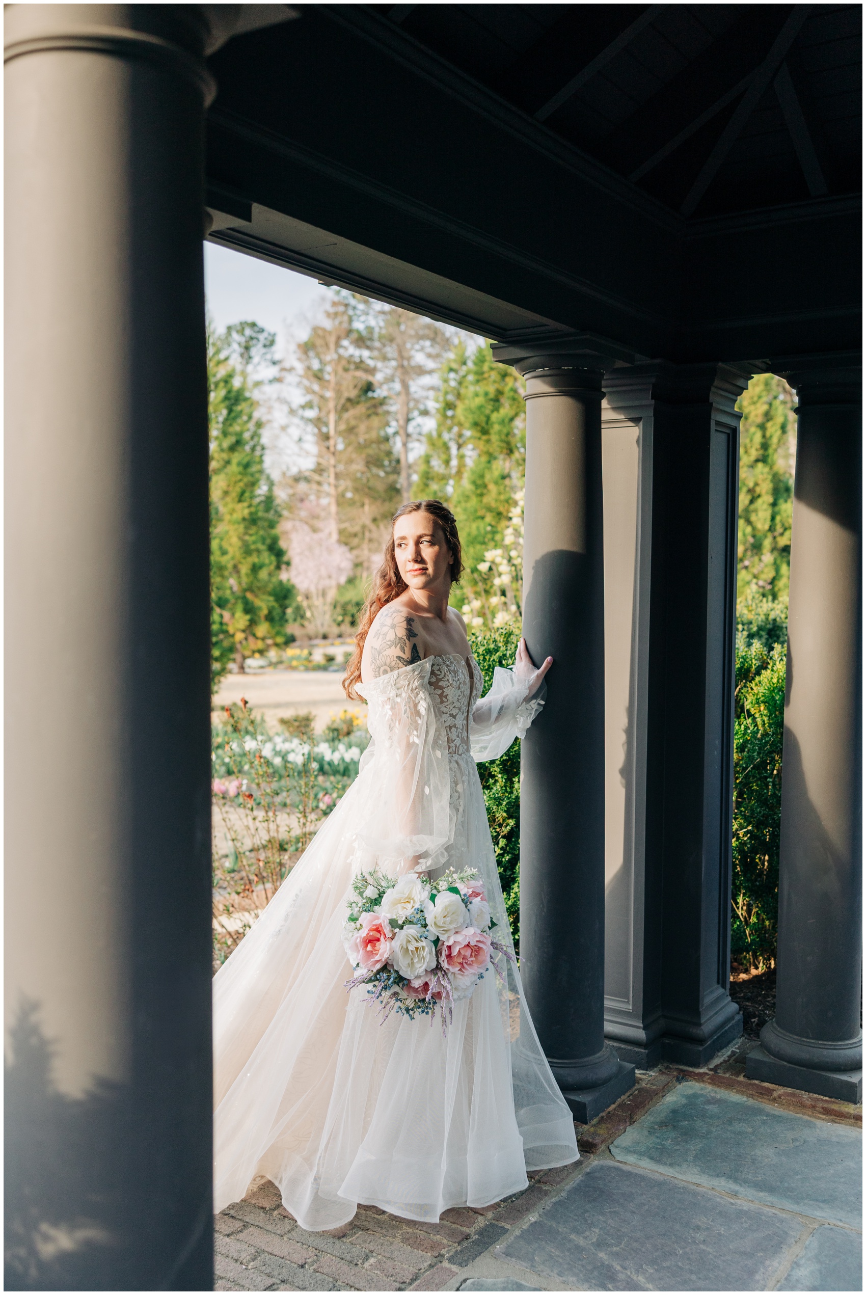 A bride stands under a gazebo with a hand on a column looking over her shoulder
