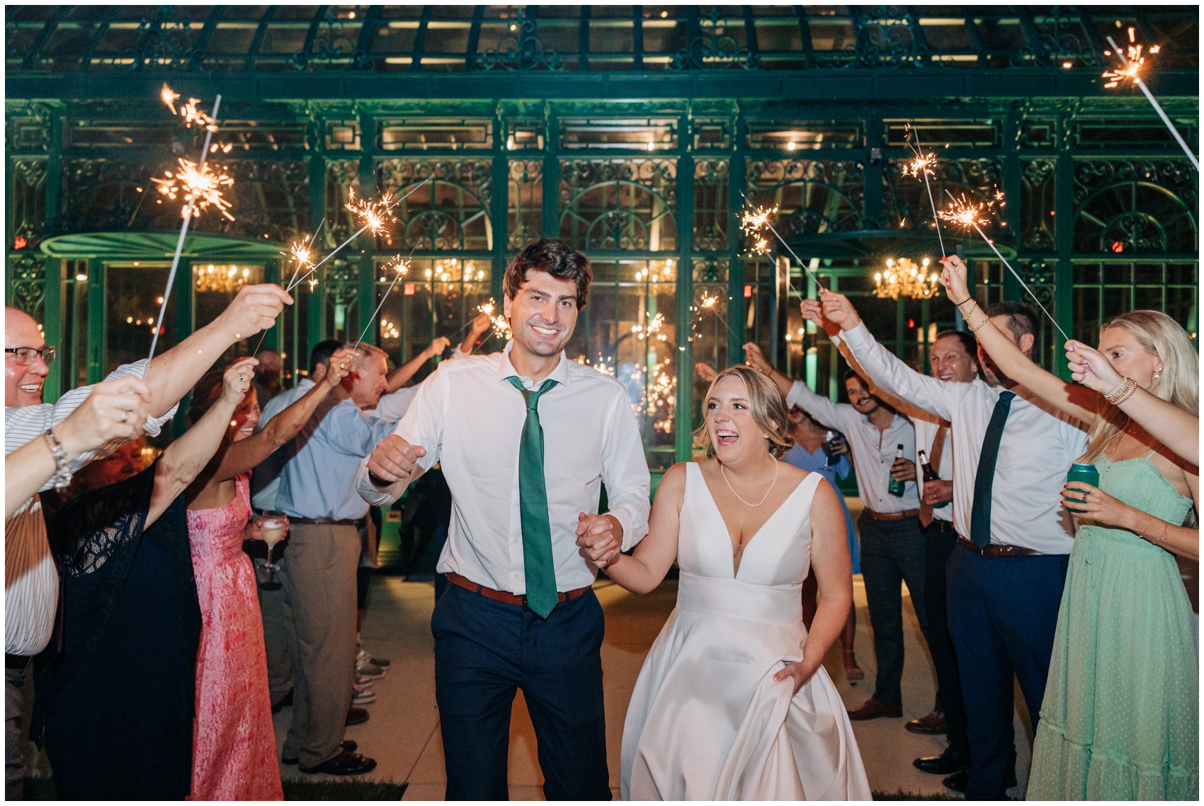 Newlyweds smile big while holding hands and exiting under sparklers at one of the Winston Salem Wedding Venues