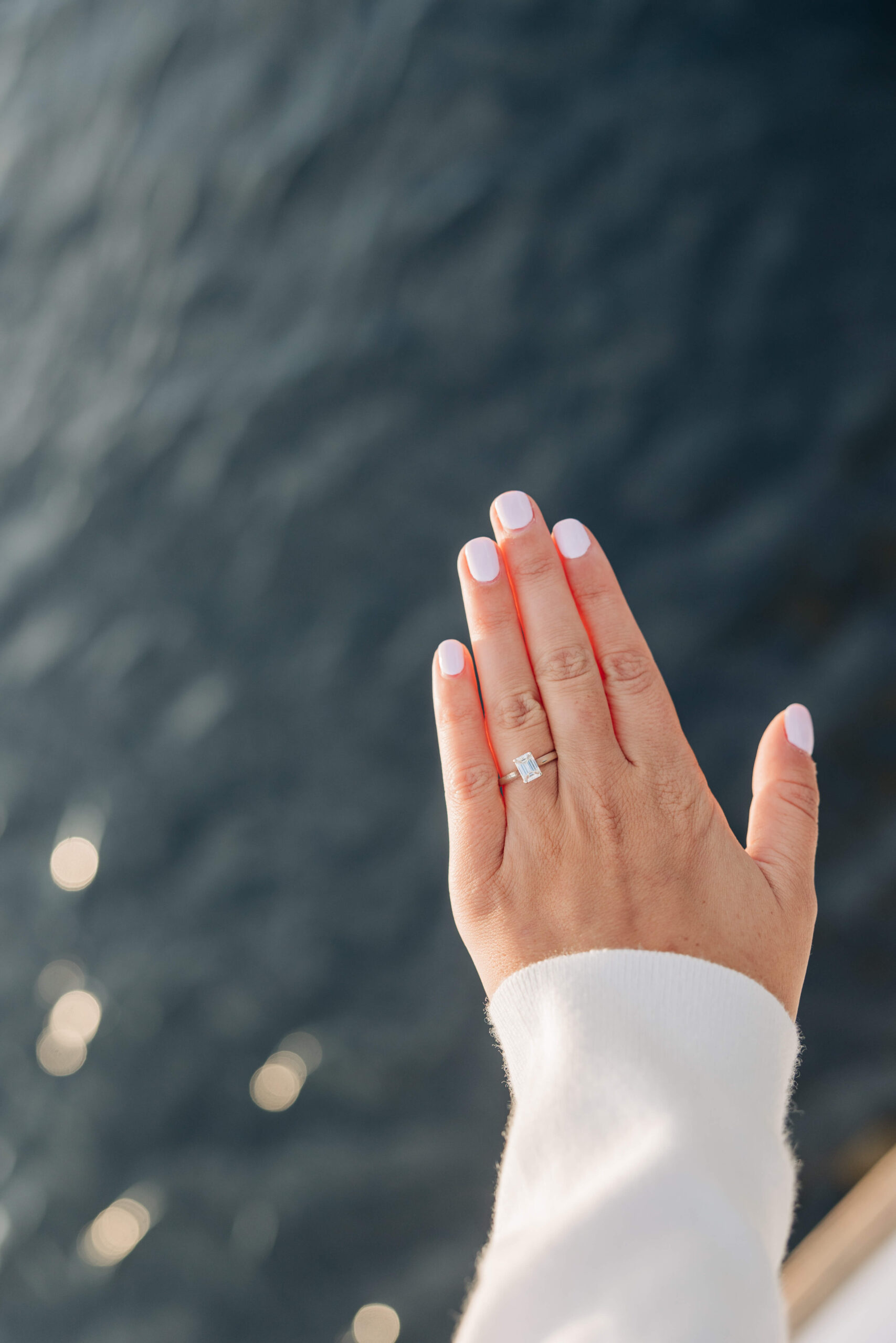Details of a woman's engagement ring on her hand on a boat