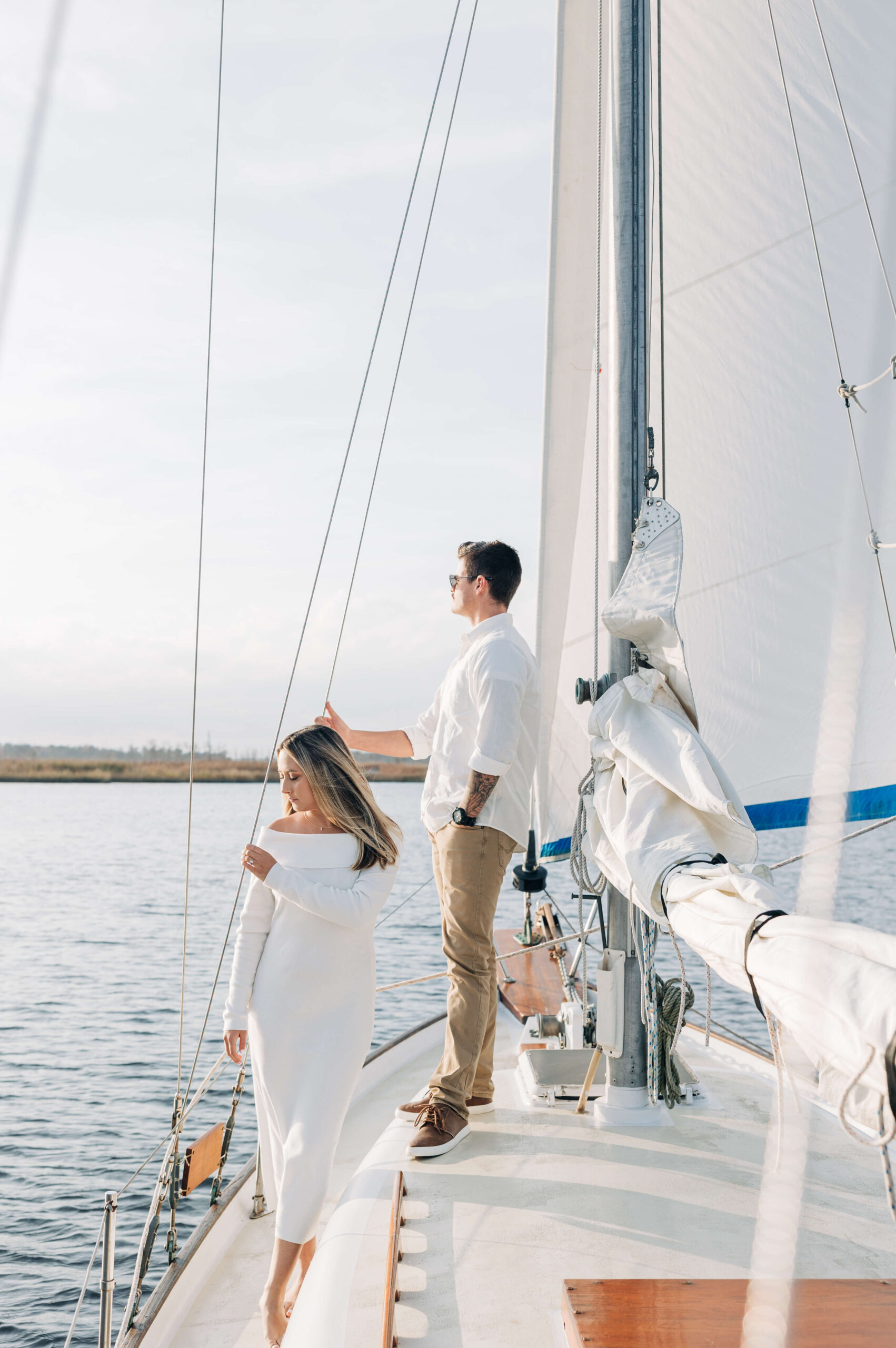 A couple admire the sunset from a sailboat while dressed in white