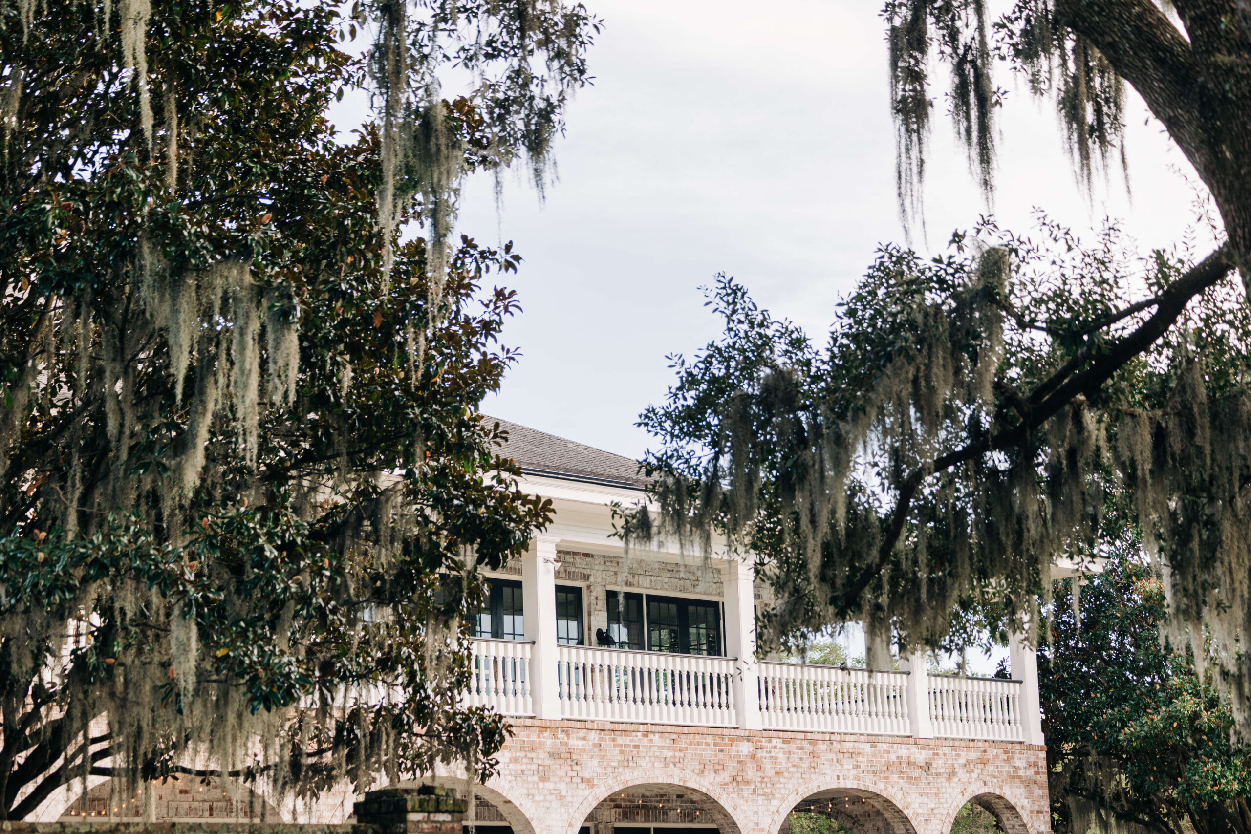 A look up to the Dunes West Golf Club wedding venue balcony through the oak trees