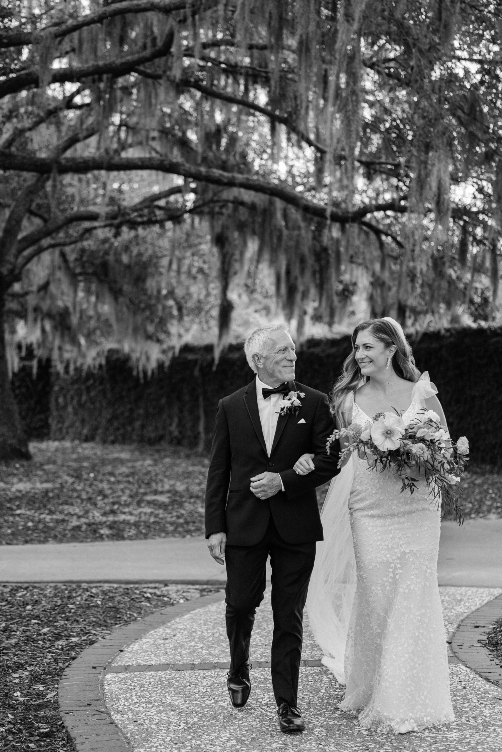 A black and white image of a proud dad walking his daughter down the aisle