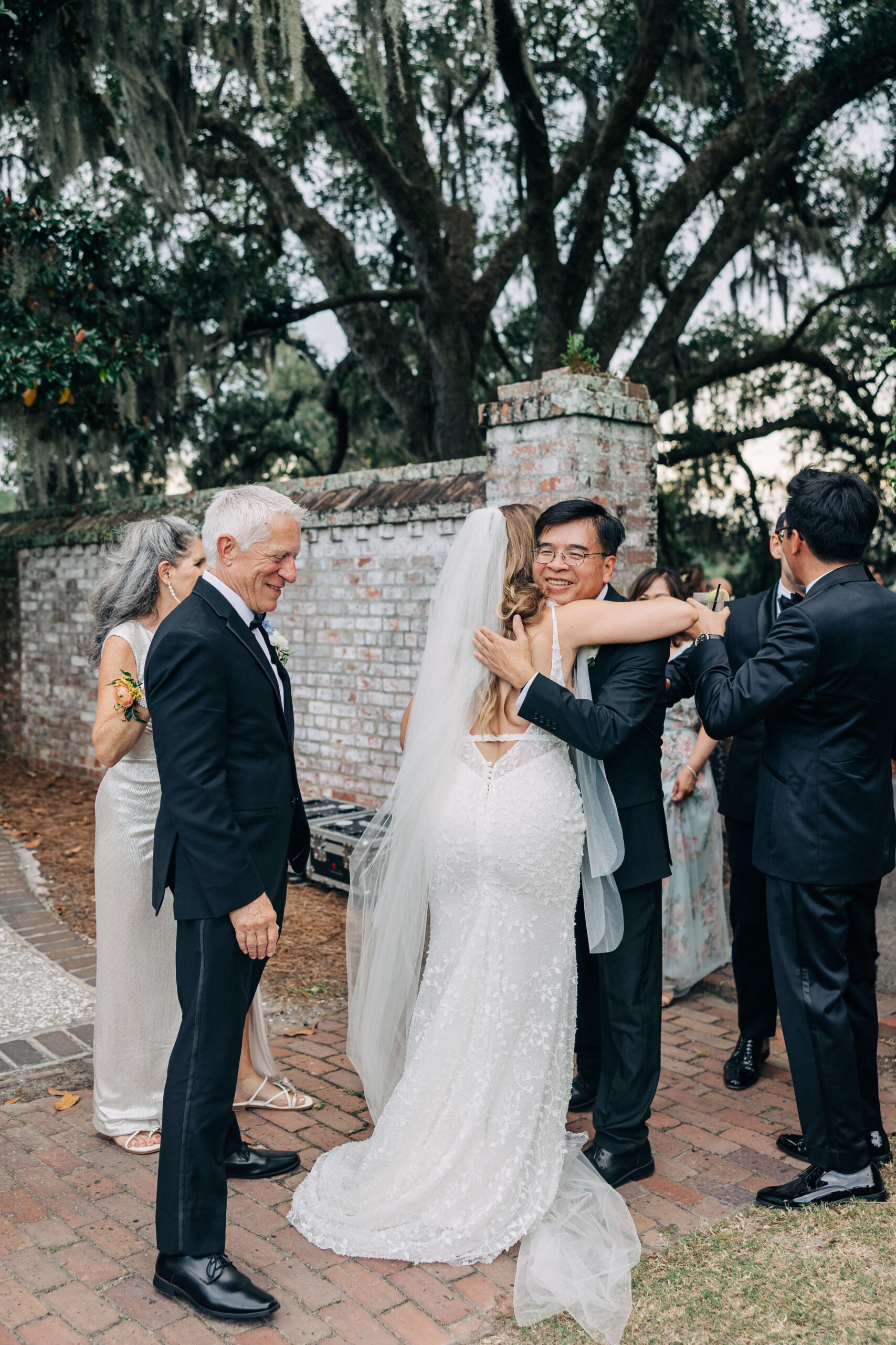A bride hugs her father in law in a garden patio