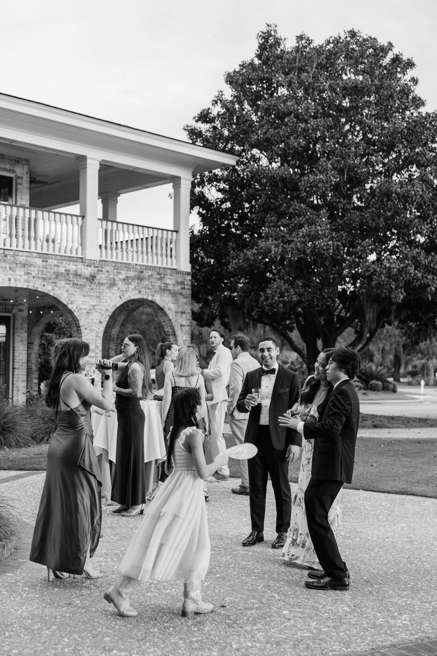 Wedding guests chat and drink out on the patio during a Dunes West Golf Club wedding reception