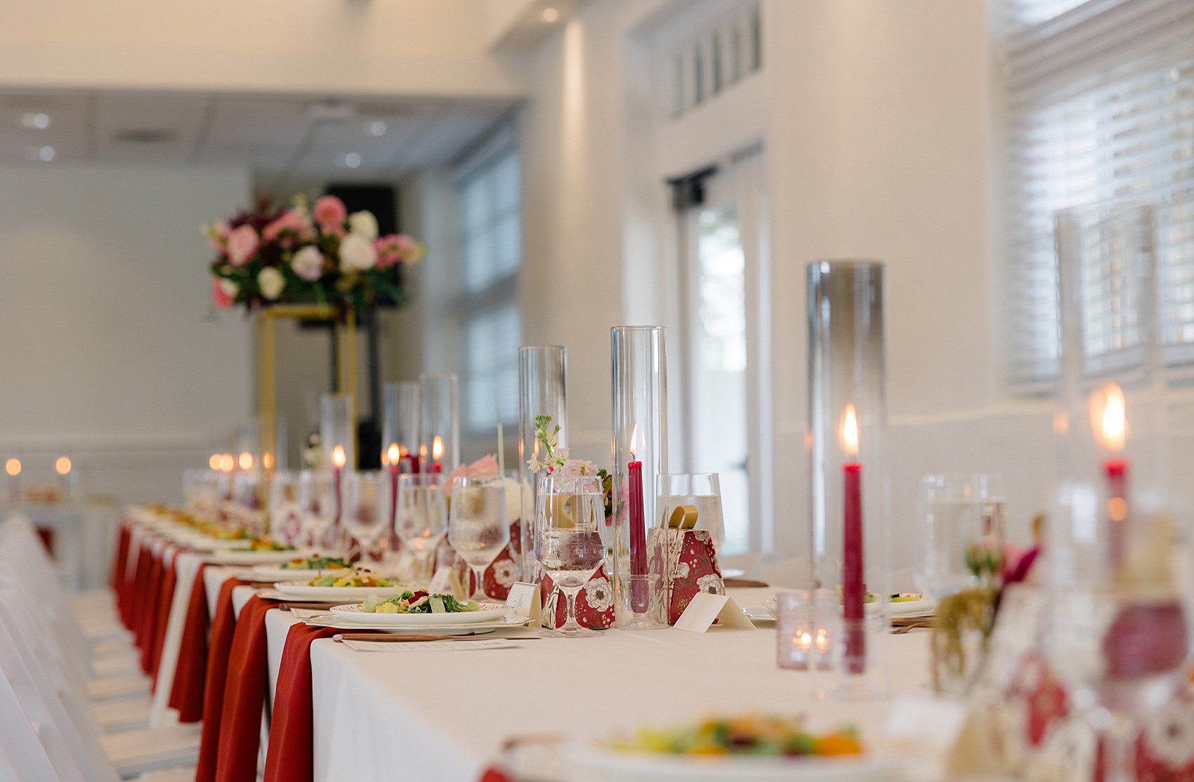 Details of a long wedding reception table at the barn at reynolda village wedding venue with red candles and napkins